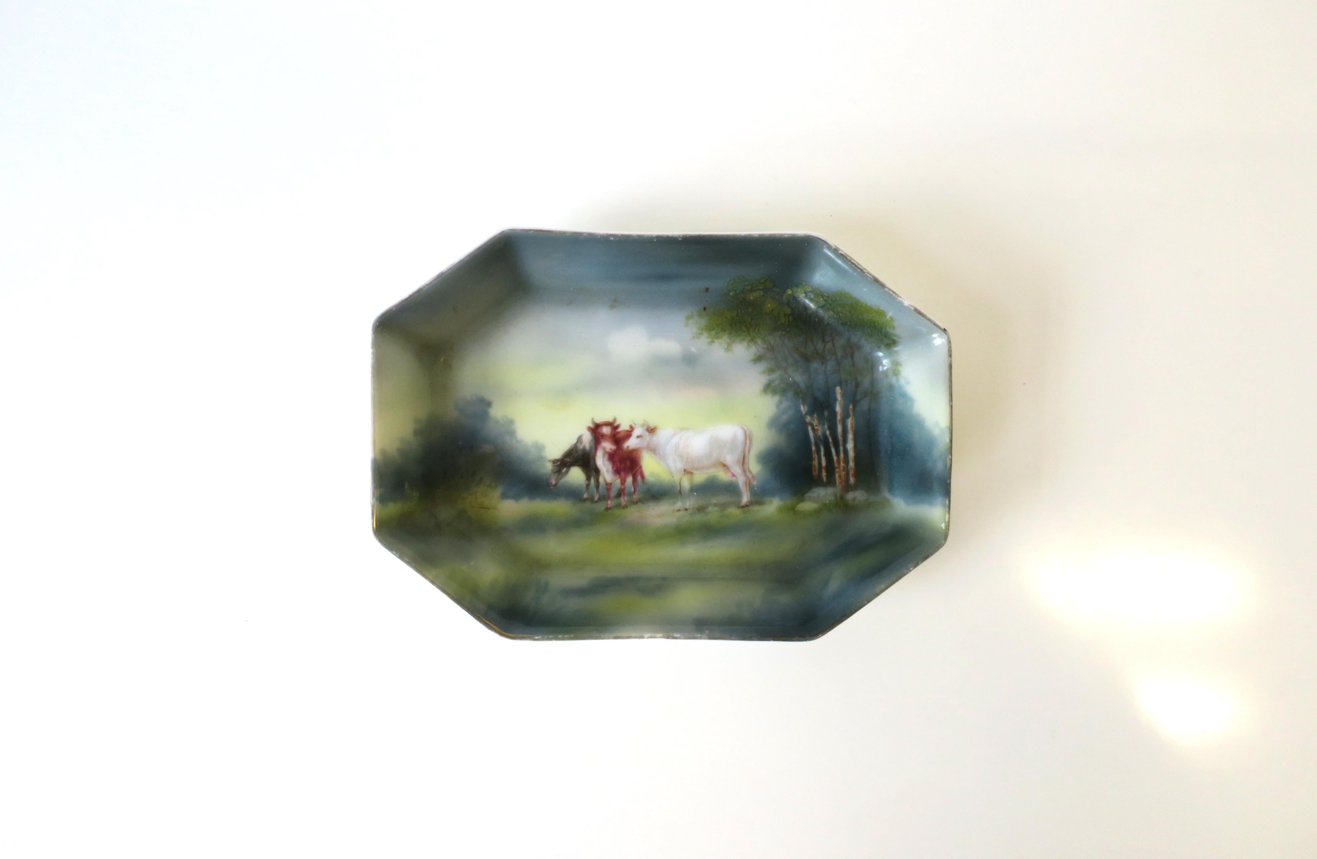 A very beautiful German porcelain jewelry dish with farm scene, circa early-20th century, Germany. Dish is octagonal in shape with luminous rustic landscape farm scene of three bovine cows, grazing, amongst the trees. Great as a standalone piece, or