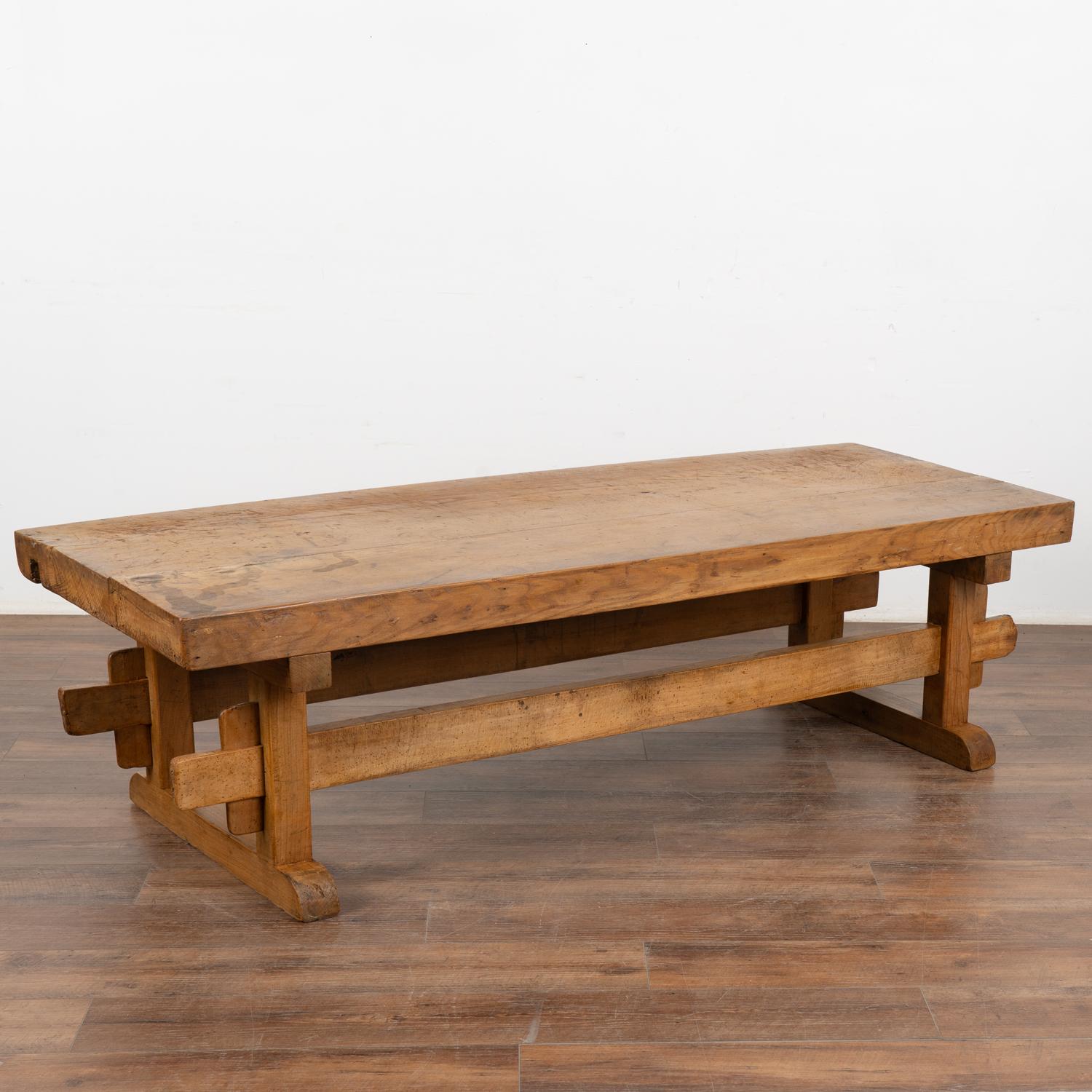 Rustic 6' farmhouse coffee table with trestle style base and loaded with vintage character.
The thick plank wood top is covered in scrapes, deep gouges, stains and old cracks acquired with 100 years of use as a work table.
Restored and waxed, this