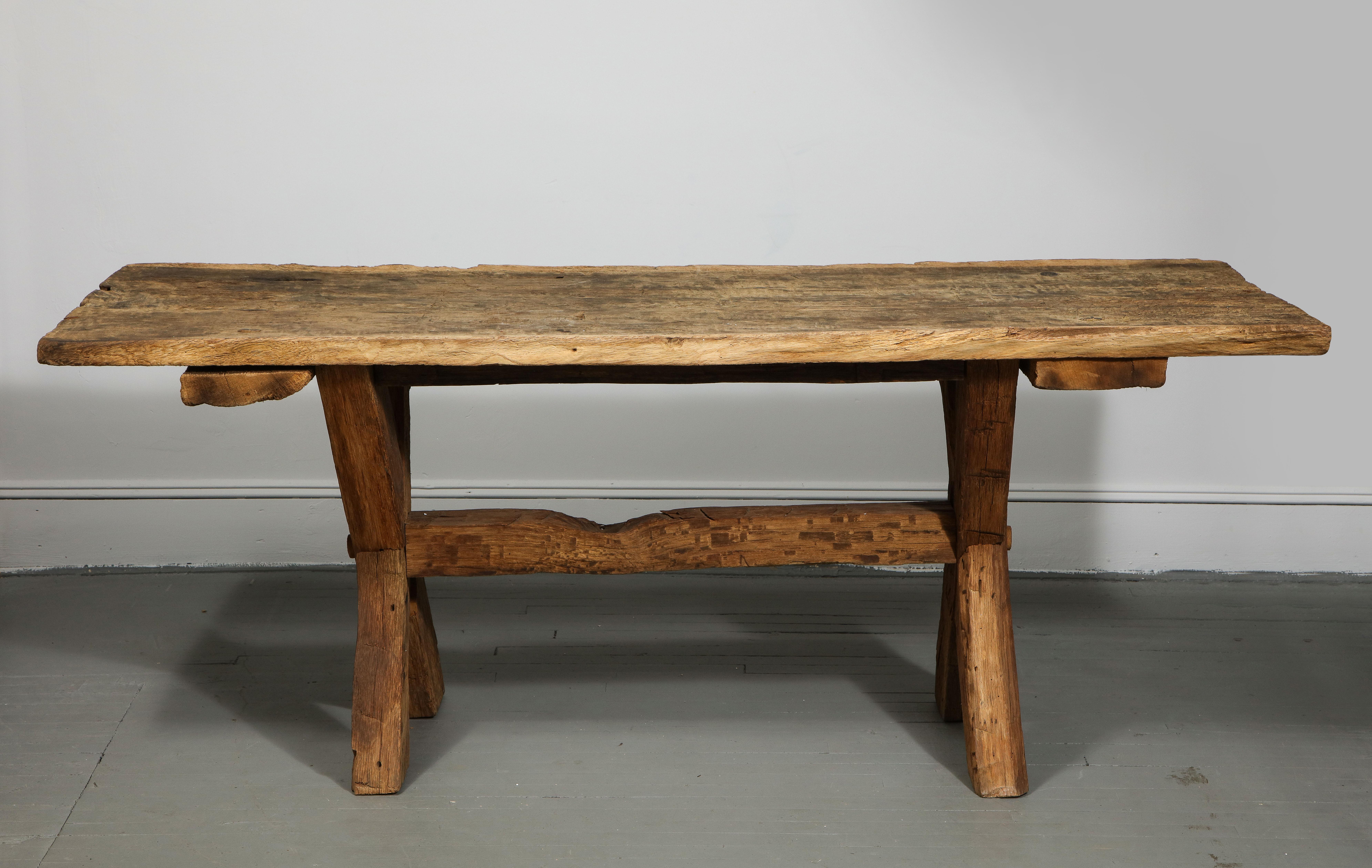 Charming rustic farmhouse table with handsome trestle base and delightfully aged top. 

Table is structurally sound and displays a beautiful, authentic patina that is consistent with both its use and age. 

 