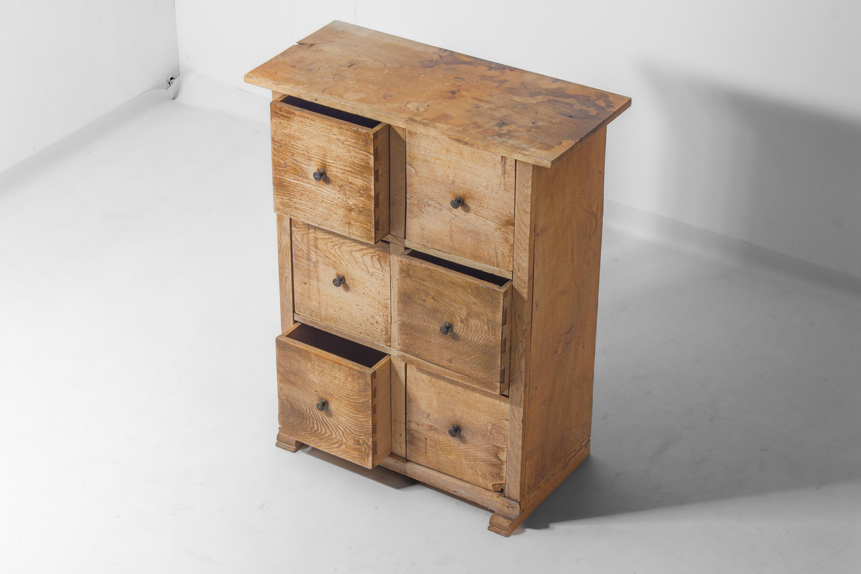 Cette commode en bois massif provient de la France rurale et date du début des années 1900. Il comporte six tiroirs avec des boutons en fer ornés et une surface naturelle et usée par le temps qui montre son âge et son utilisation. Construit de