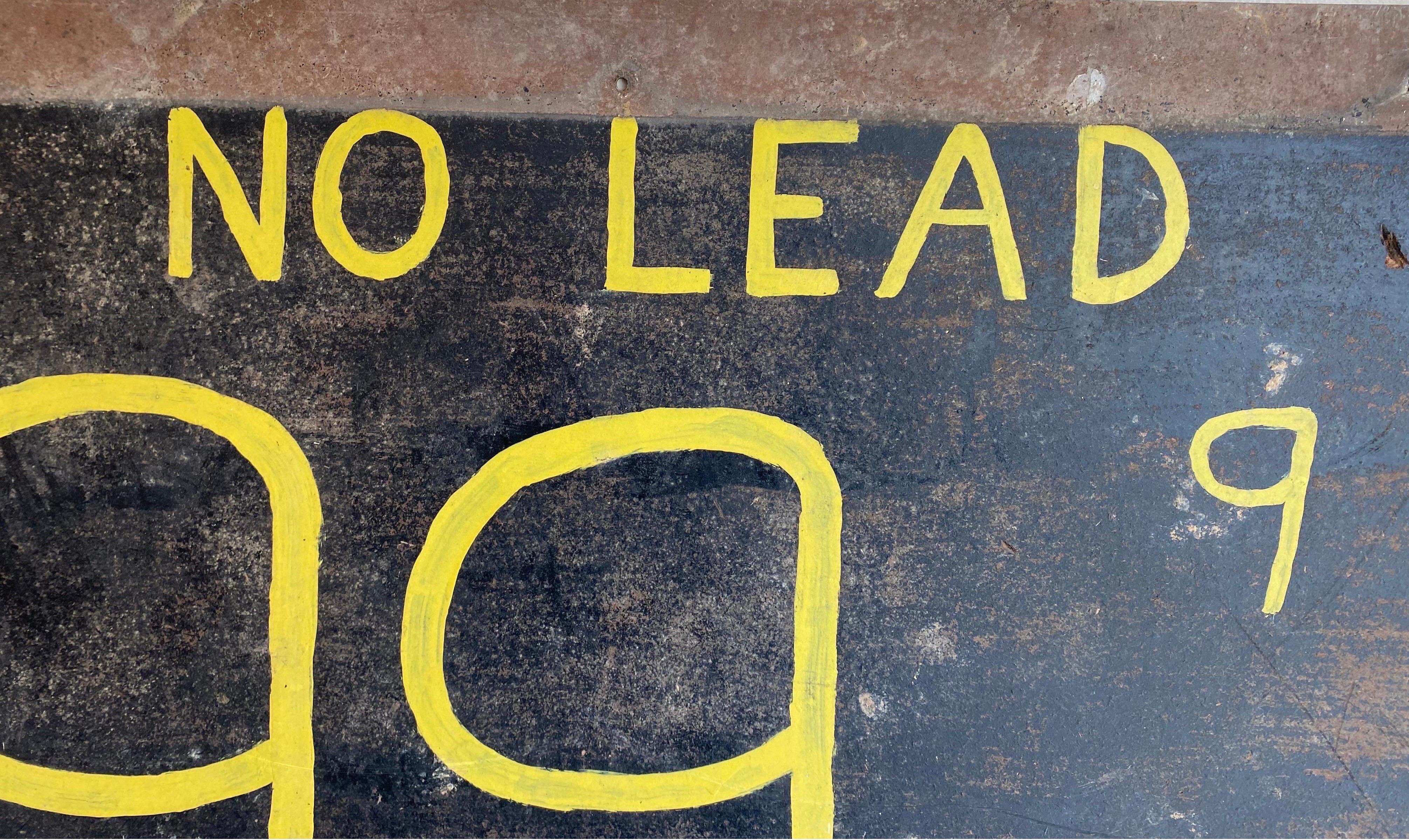 Vintage handcrafted gas station signage on board. The sign dates to pre 1975 when leaded gasoline was phased out. The state states “No Lead 99.9”, painted in yellow paint on a black fiberboard.