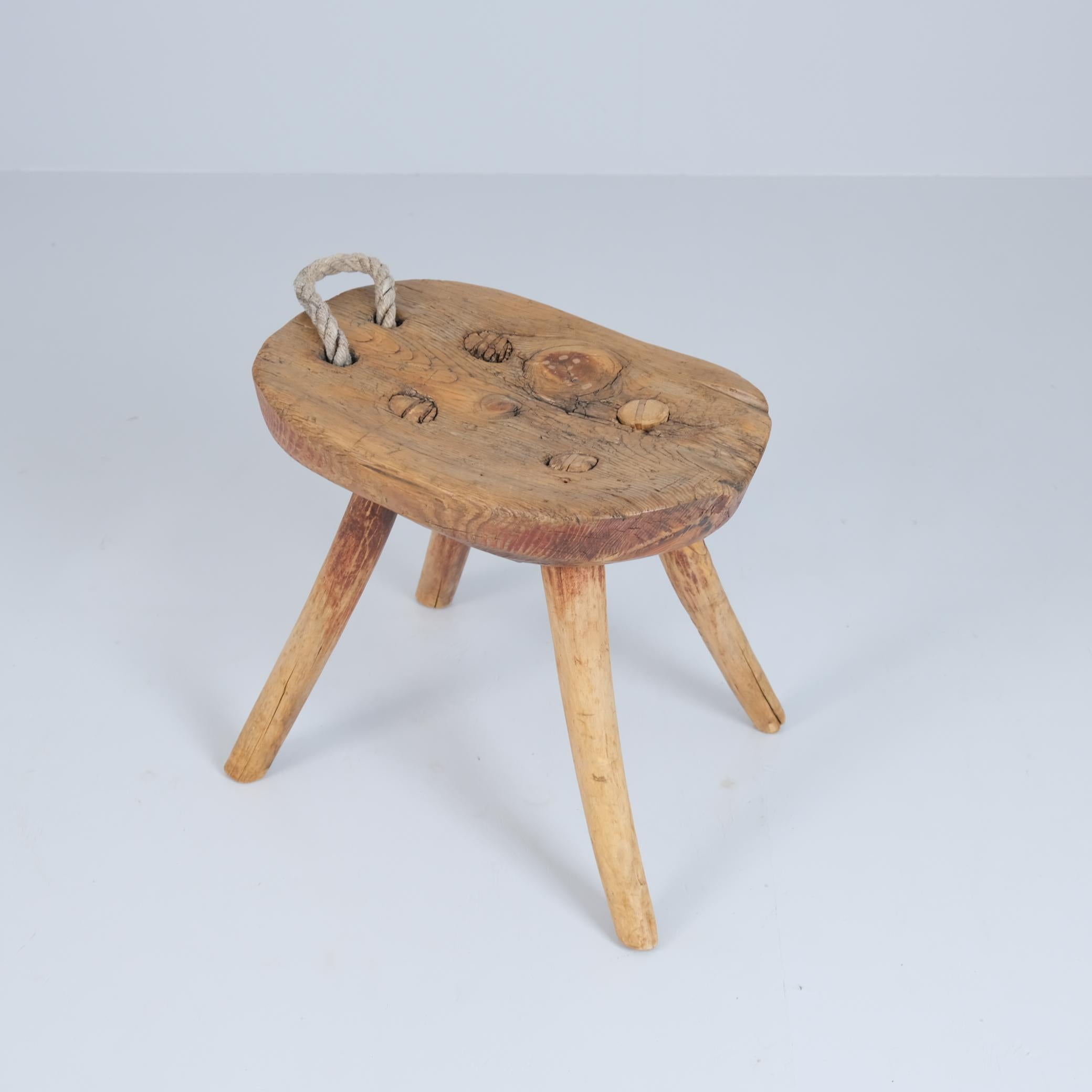 Sgabello rustico da contadino finlandese di fine '800, realizzato a mano in legno massiccio con una splendida patina invecchiata. Originariamente realizzato con uno schienale, questo esemplare è stato adattato nel tempo con una robusta maniglia in