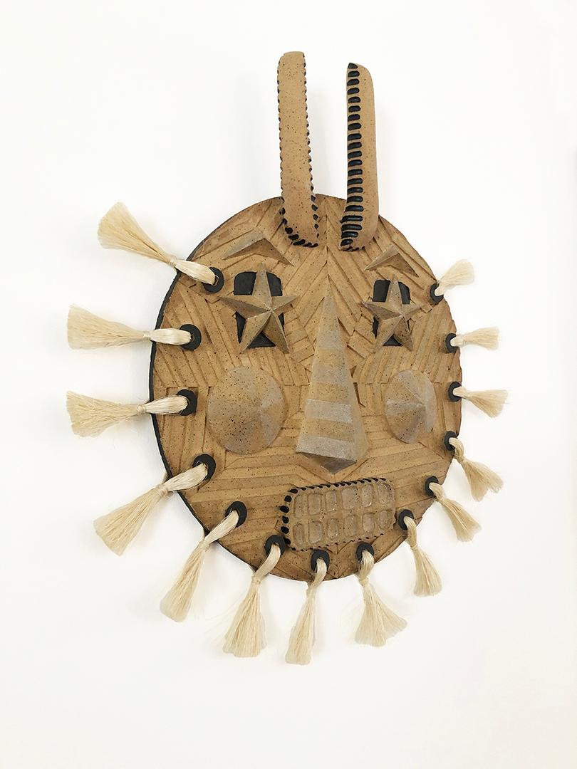 Hand sculpted and carved, wall-mounted, ceramic stoneware mask with matte black and white details and handmade sisal tassel. Designed and made by Keavy Murphree, USA, 2018.
 