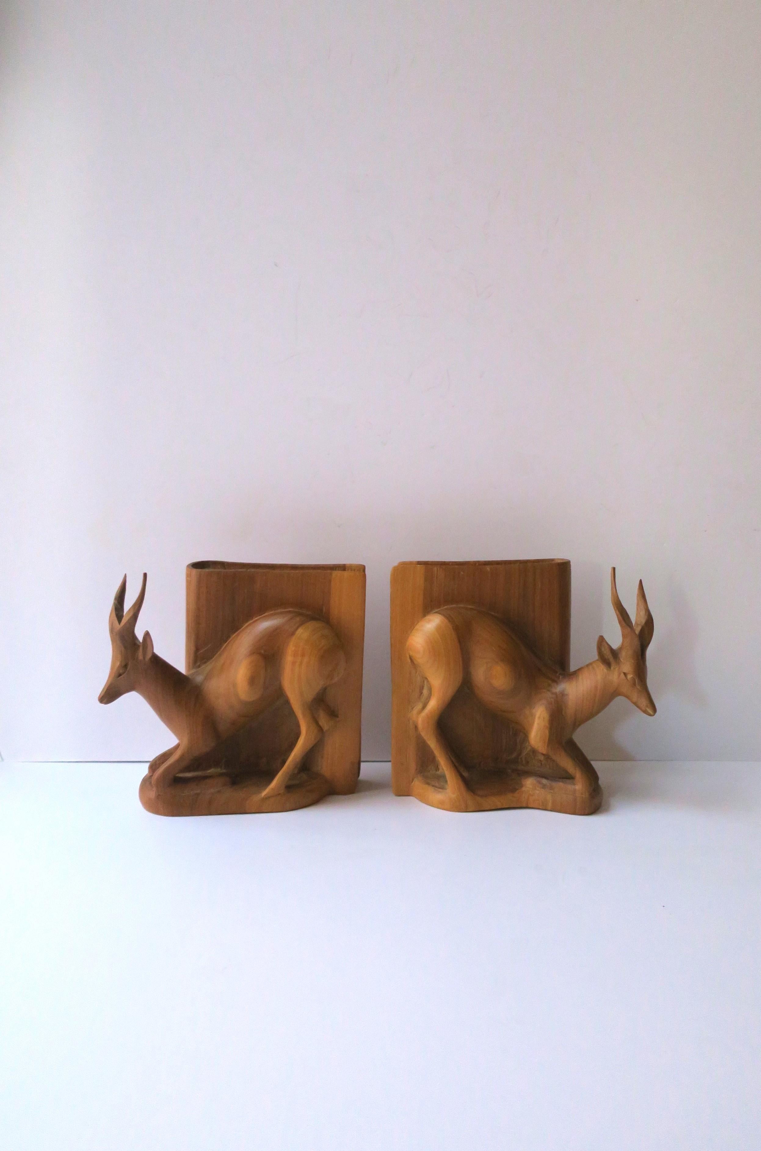 A pair Giselle or stag deer buck animal carved wood bookends in the Rustic style, circa mid to late-20th century, Sweden. Animal is carved against a 'book'. A great set for a library, office, bookshelf, ski-house, ski-lodge, hotel, etc. Dimensions: