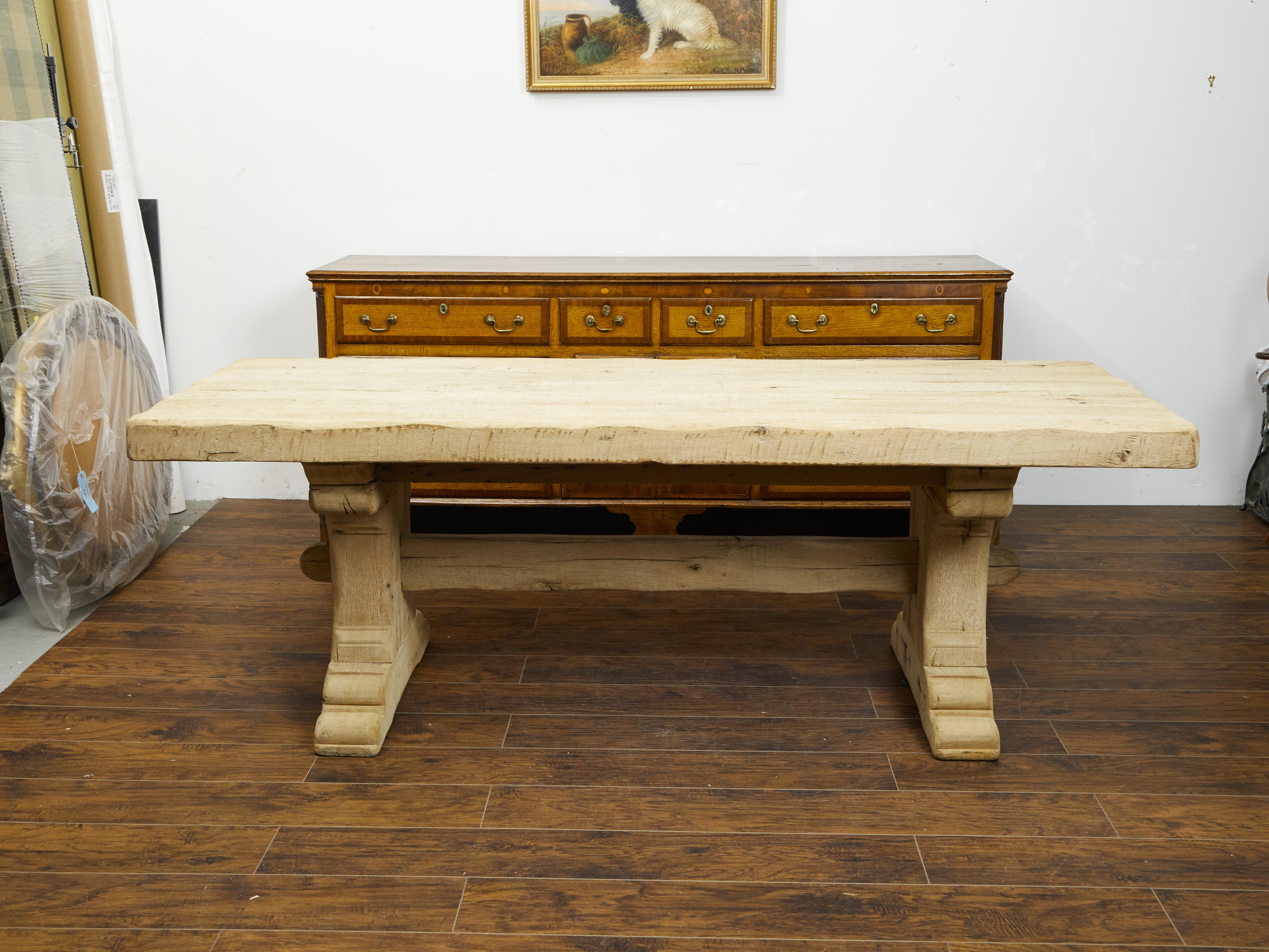 A French oak farm table from the late 19th century, with trestle base and natural patina. Created in France during the last quarter of the 19th century, this trestle table features a rectangular top sitting above a trestle base showing a nicely