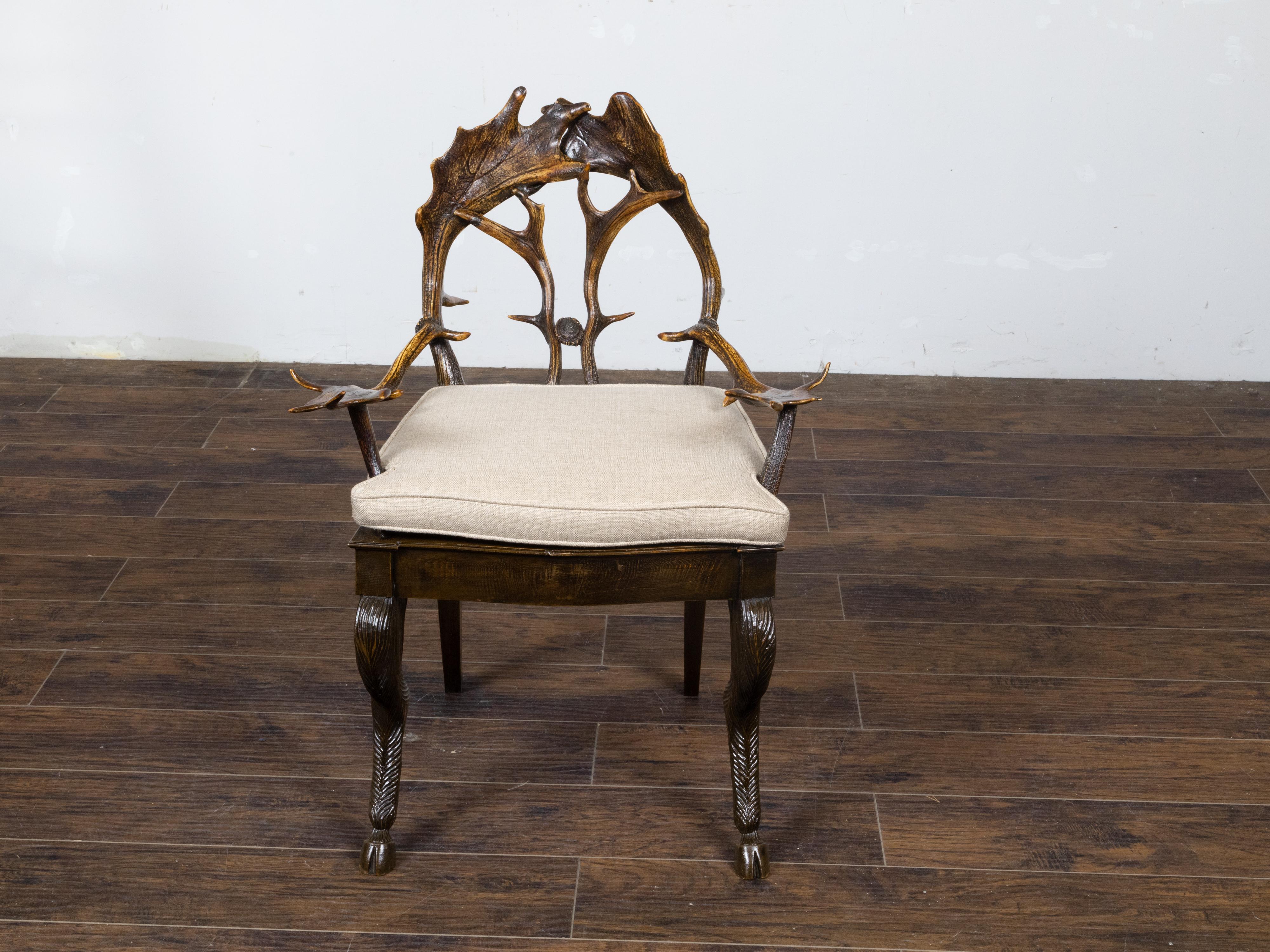 A French rustic  armchair circa 1880 with antlers back, arms, custom linen cushion and carved animal legs. This French armchair, dating back to the last quarter of the 19th century, will instantly enchants the viewer with its rustic antlers back,