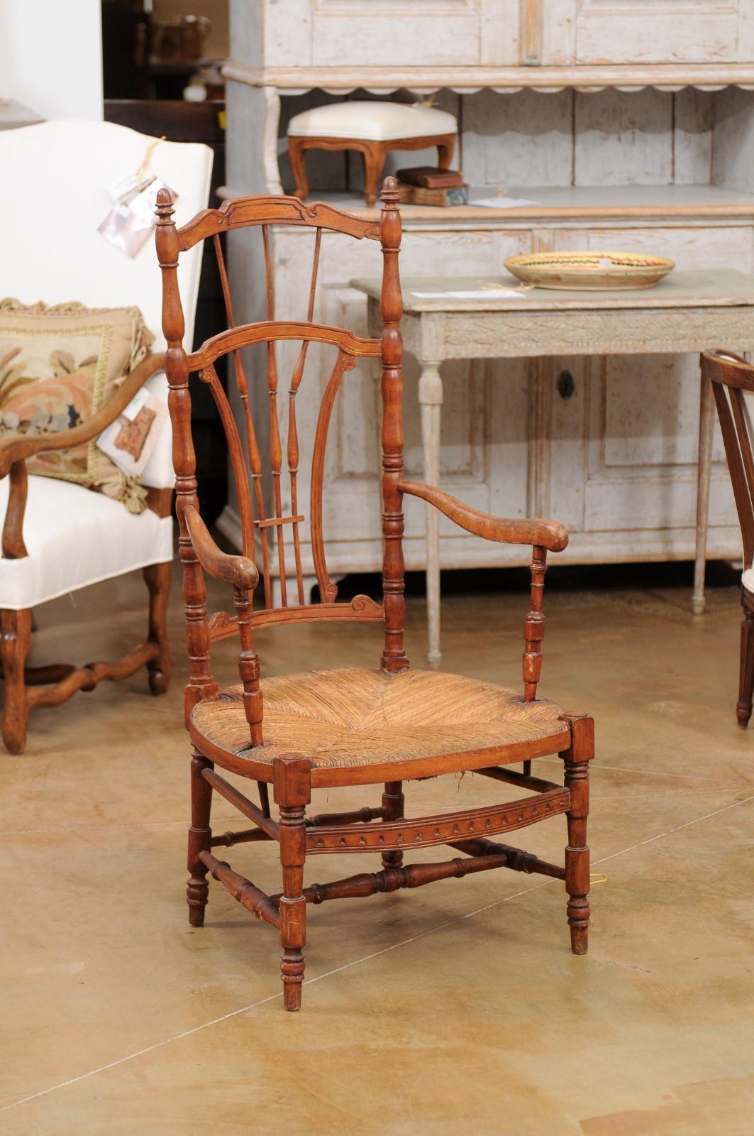 A rustic French cherry wood armchair from the late 19th century, with rush seat and sheaf back. Created in France during the last decade of the 19th century, this cherry wood armchair charms us with its rustic appeal and turned accents. The chair