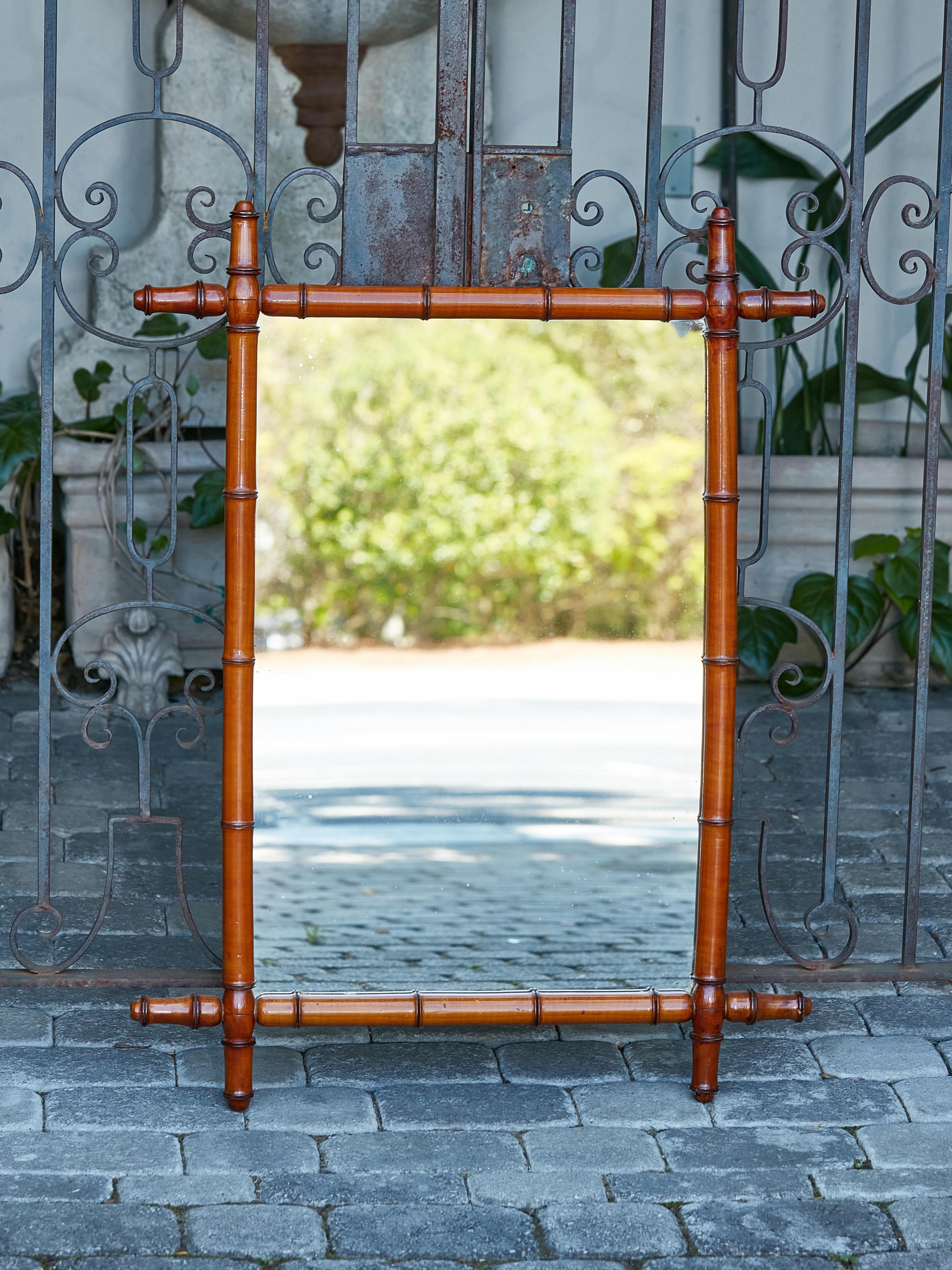 A French walnut faux-bamboo mirror from circa 1920 with honey brown color, intersecting corners and rustic character. Introducing a charming piece from the Roaring Twenties – this French walnut faux-bamboo mirror, circa 1920, is a timeless treasure