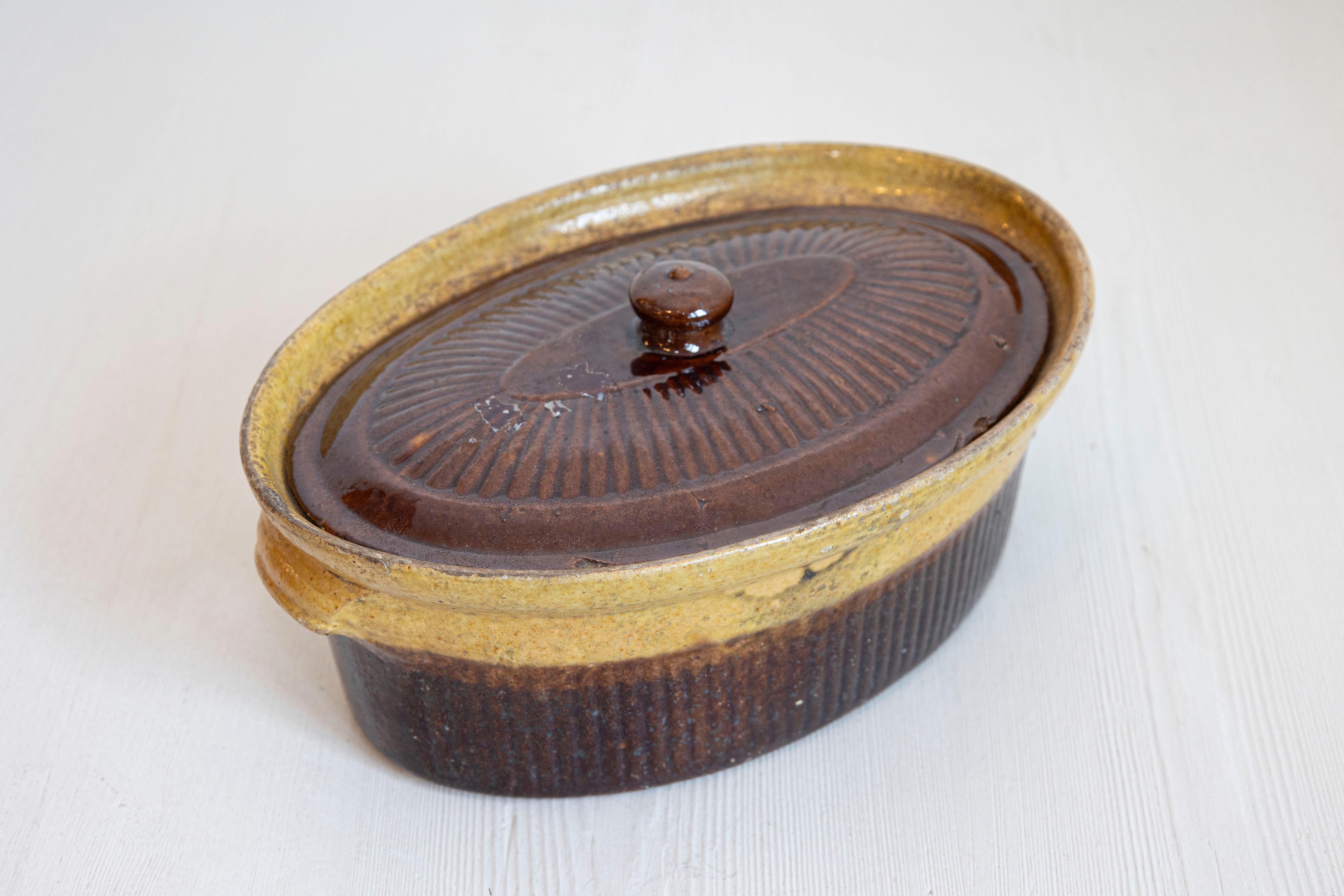 Una rustica zuppiera da paté francese del XIX secolo con smalto marrone. Creata in Francia nel XIX secolo, questa terrina presenta un corpo ovale tradizionale sormontato da un coperchio e affiancato da leggeri manici. Con uno smalto marrone e oro,