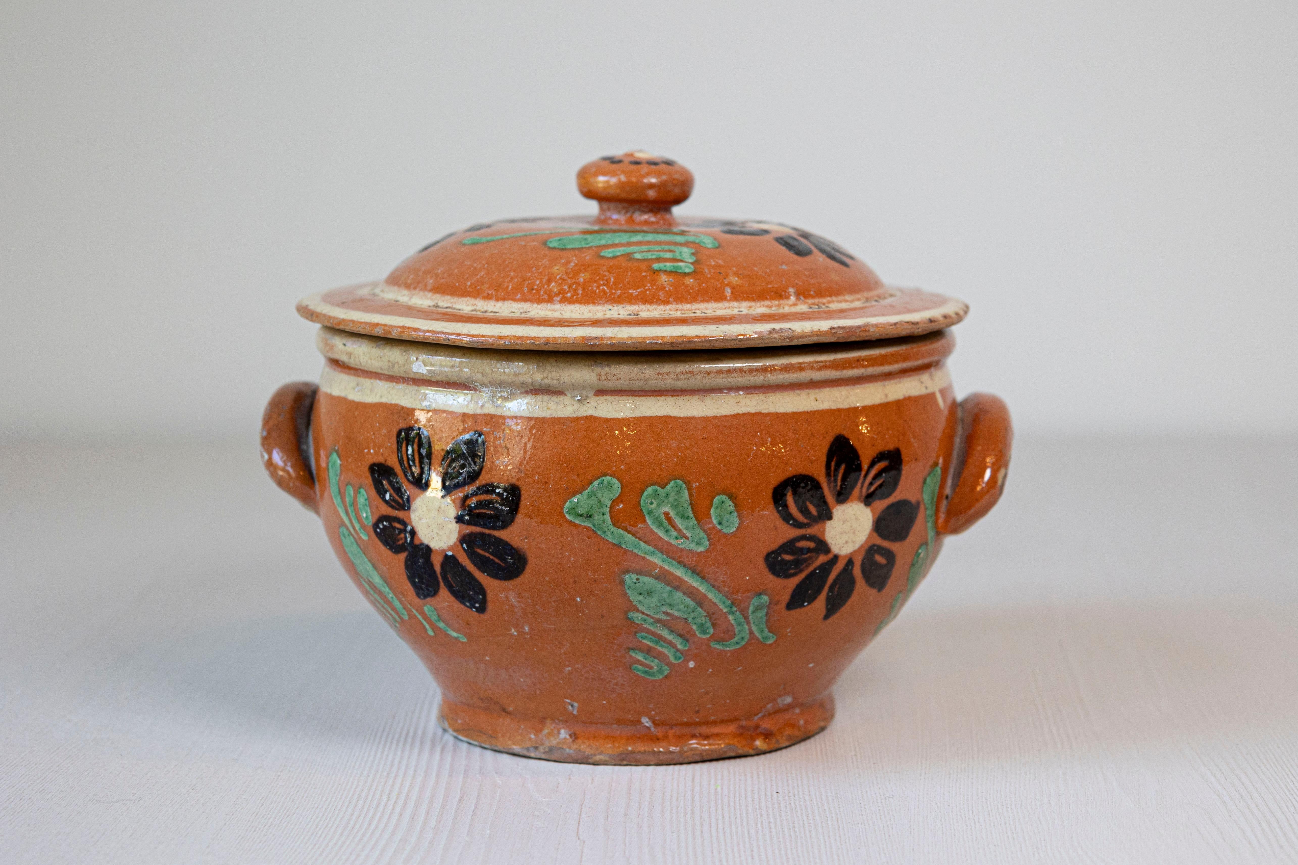 Plat à four couvert en terre cuite rustique française du XIXe siècle, avec un décor floral brun et vert. Créé en France au cours du XIXe siècle, ce plat à four couvert présente un couvercle circulaire surmonté d'une petite poignée, surmontant un