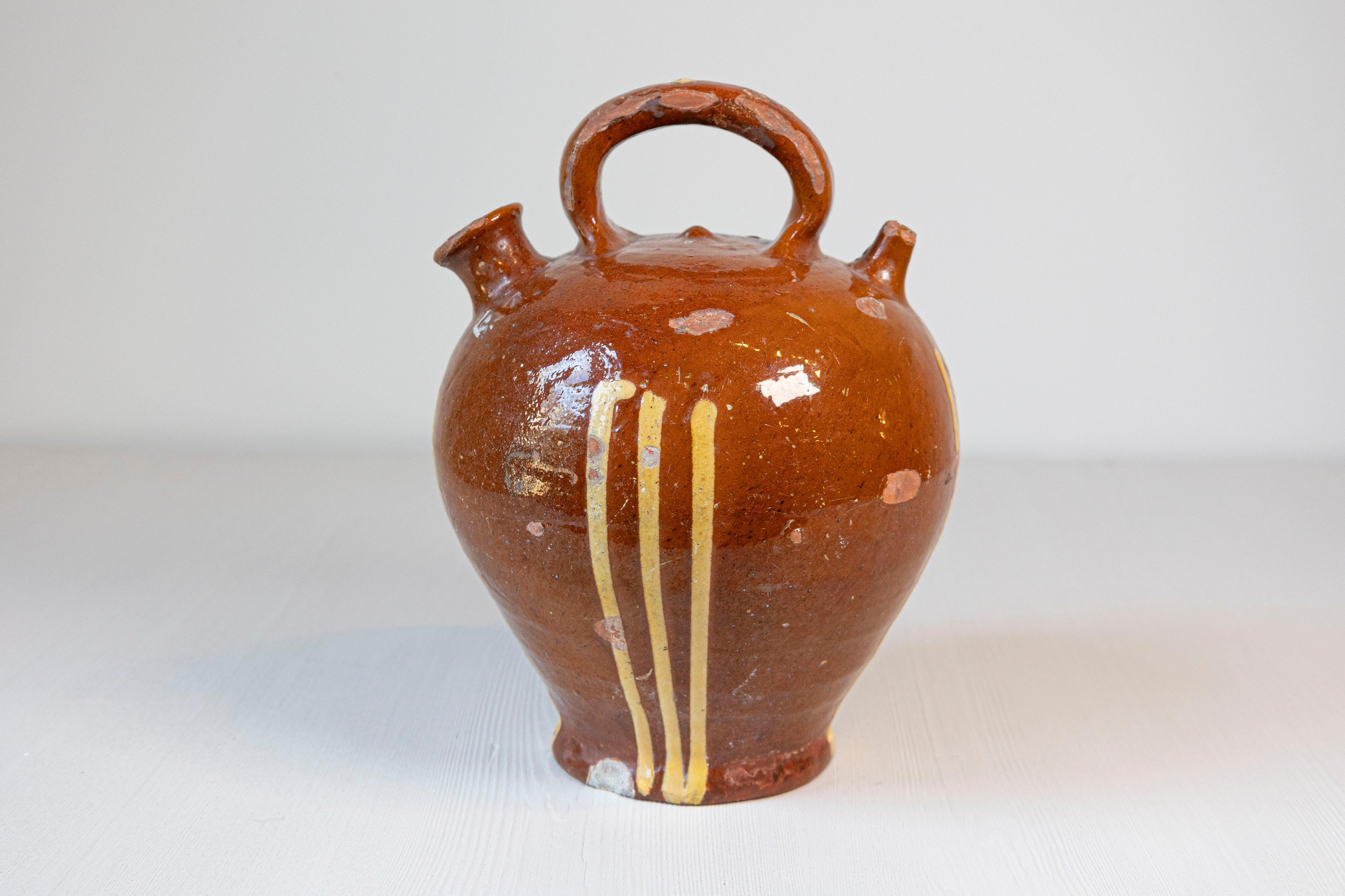Una brocca rustica in ceramica francese del XIX secolo, con fondo ruggine e strisce smaltate di giallo. Creata in Francia nel XIX secolo, questa brocca in ceramica ci affascina con le sue linee generose e i suoi colori complementari. Con un fondo