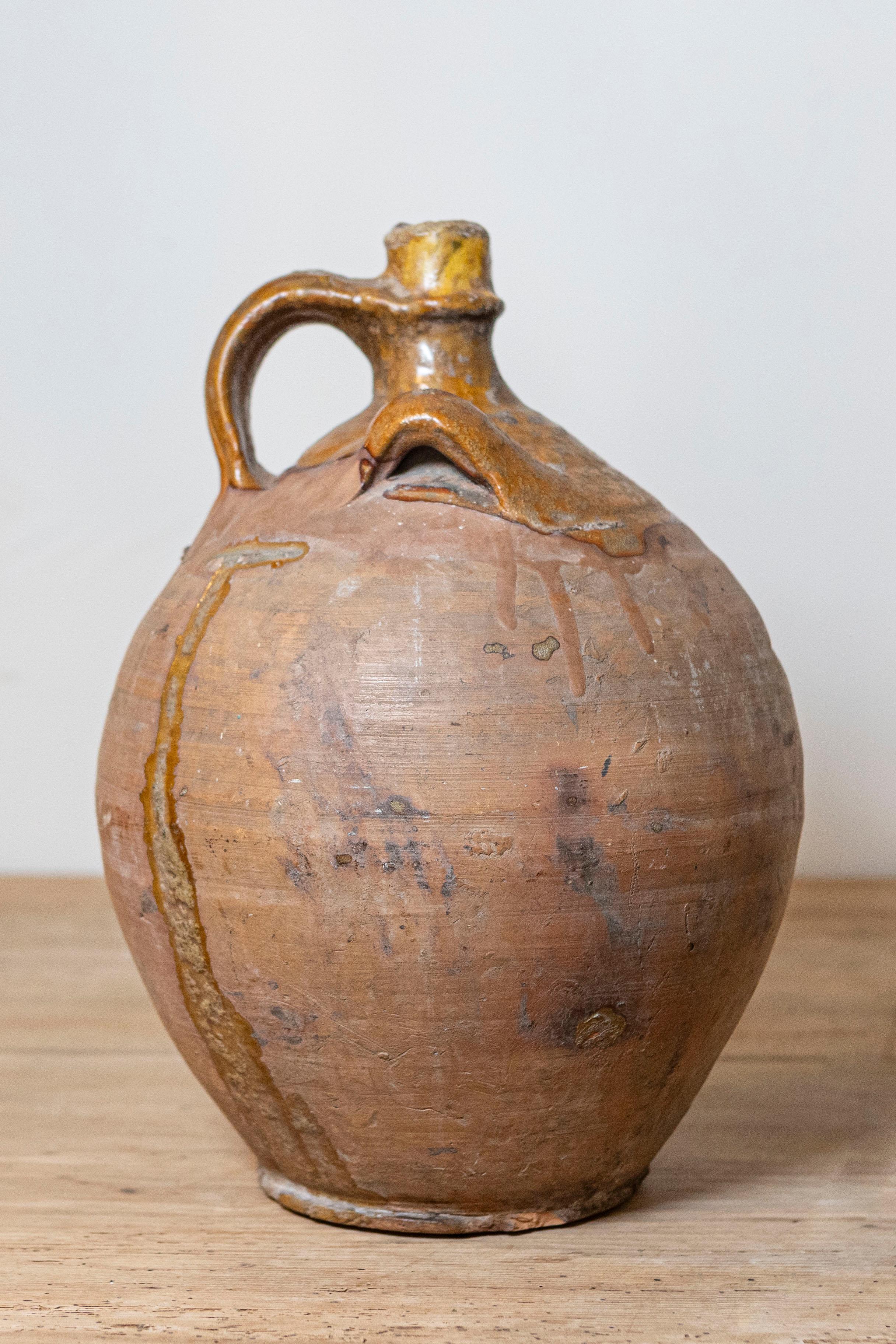  Une cruche à eau en poterie française du 19ème siècle avec une glaçure jaune et trois poignées. Enrichissez votre collection de poteries françaises avec cette charmante cruche à eau du XIXe siècle. Fabriquée à la main, cette pièce présente une