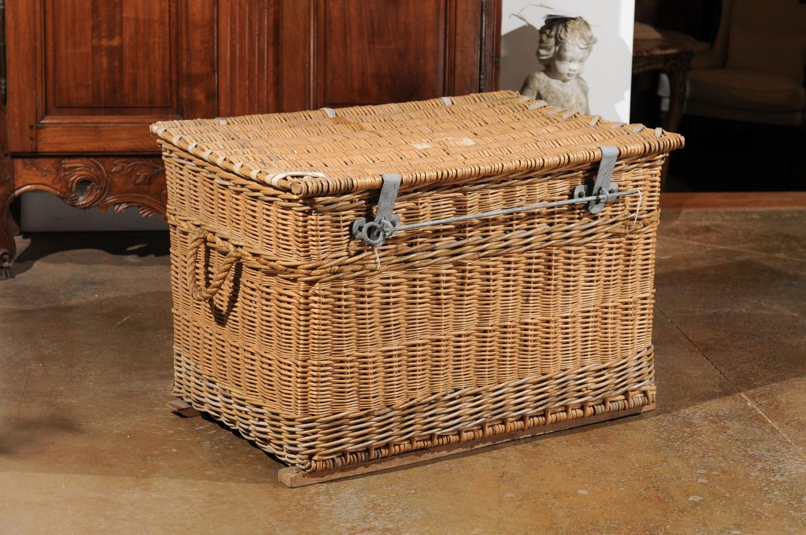 A French wicker trunk from the 19th century, with metal hardware and lateral handles. Born in France during the 19th century, this wicker trunk features a rectangular lid opening thanks to a metal bar to reveal a convenient storage space, lined with