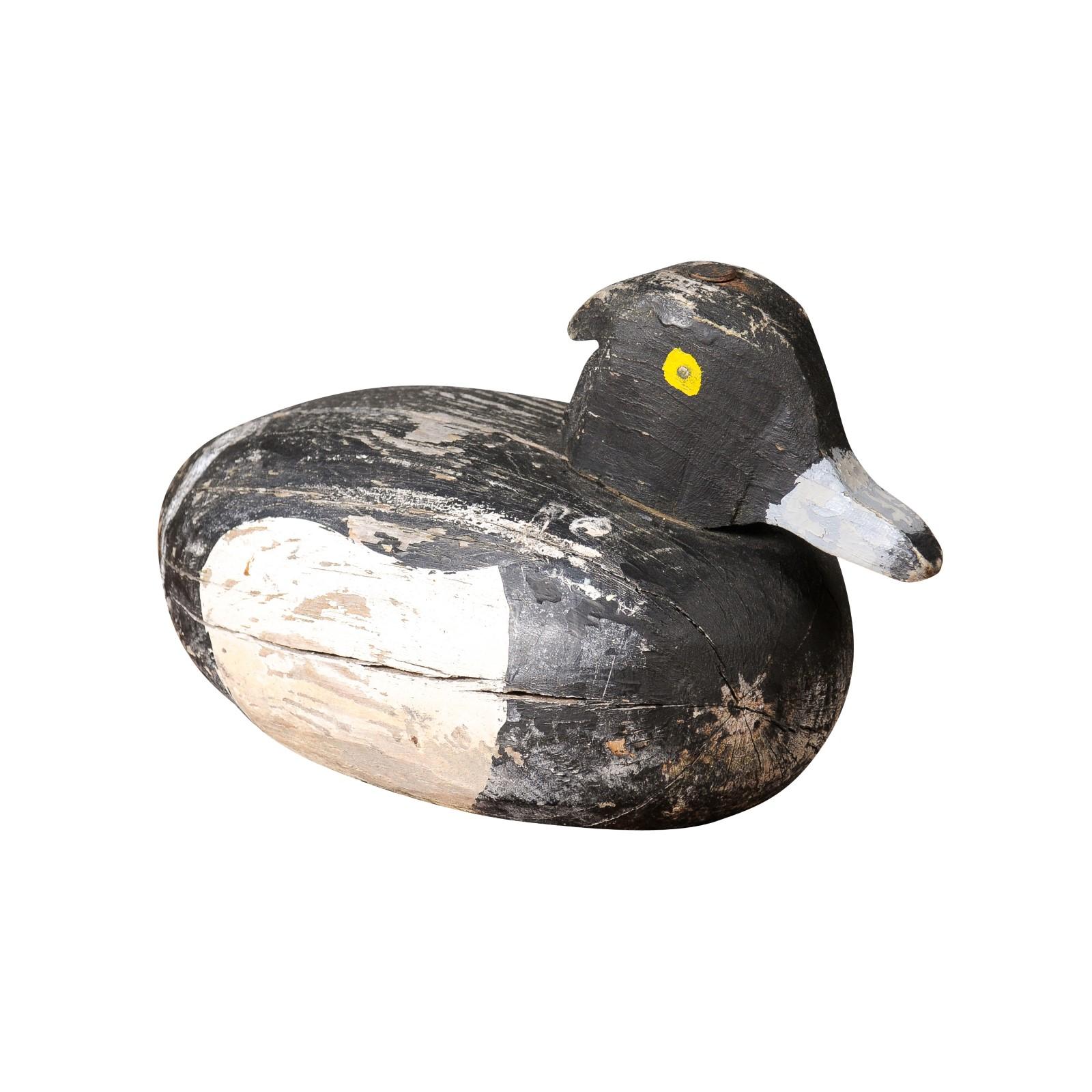 A French carved wooden duck from the 20th century with rustic appearance, white, black and yellow paint. Envelop your space with an air of tranquility and pastoral bliss with this delightful French carved wooden duck from the 20th century. A