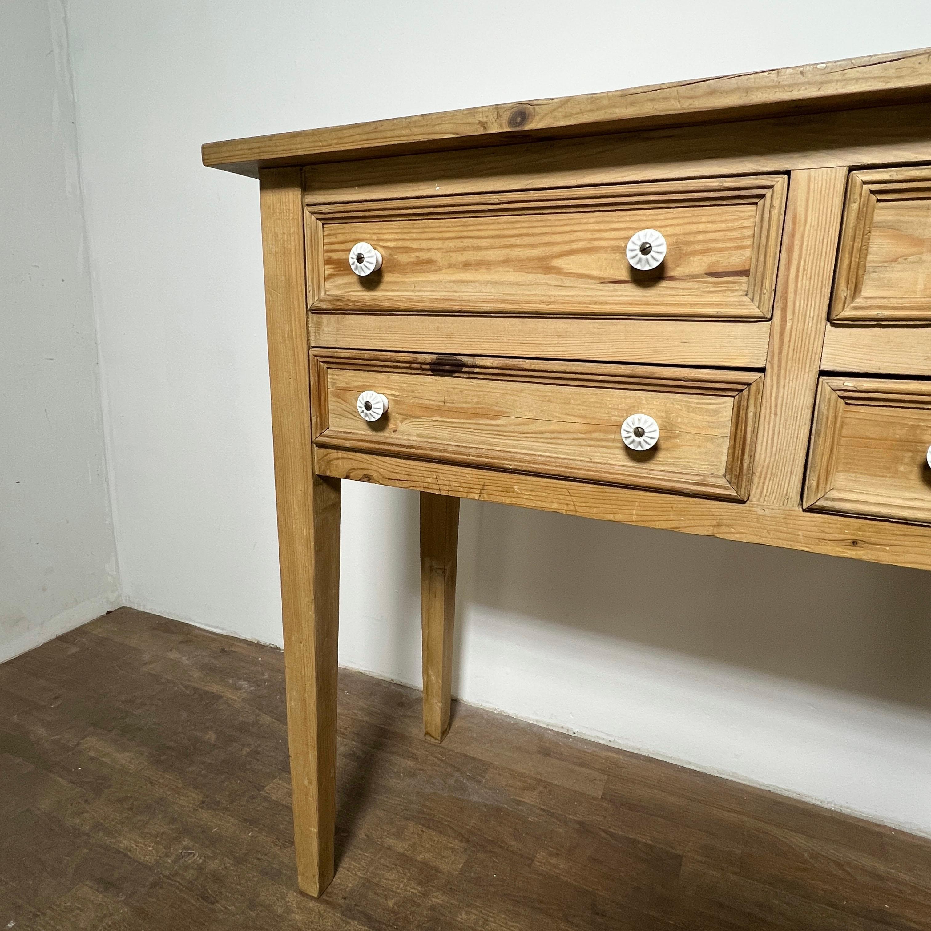 A rustic 20th century French country buffet table in stripped pine with four beaded drawers and porcelain pulls. 