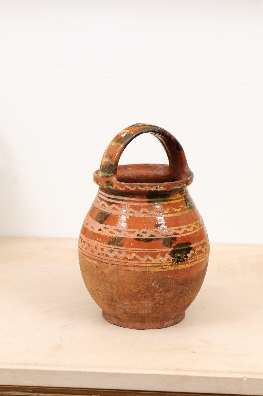A rustic French pottery jug from the late 19th century, with wavy lines and large handle. Created in France at the end of the 19th century, this pottery jug features a rusty brown glazed ground adorned with yellow and cream wavy lines and blotched