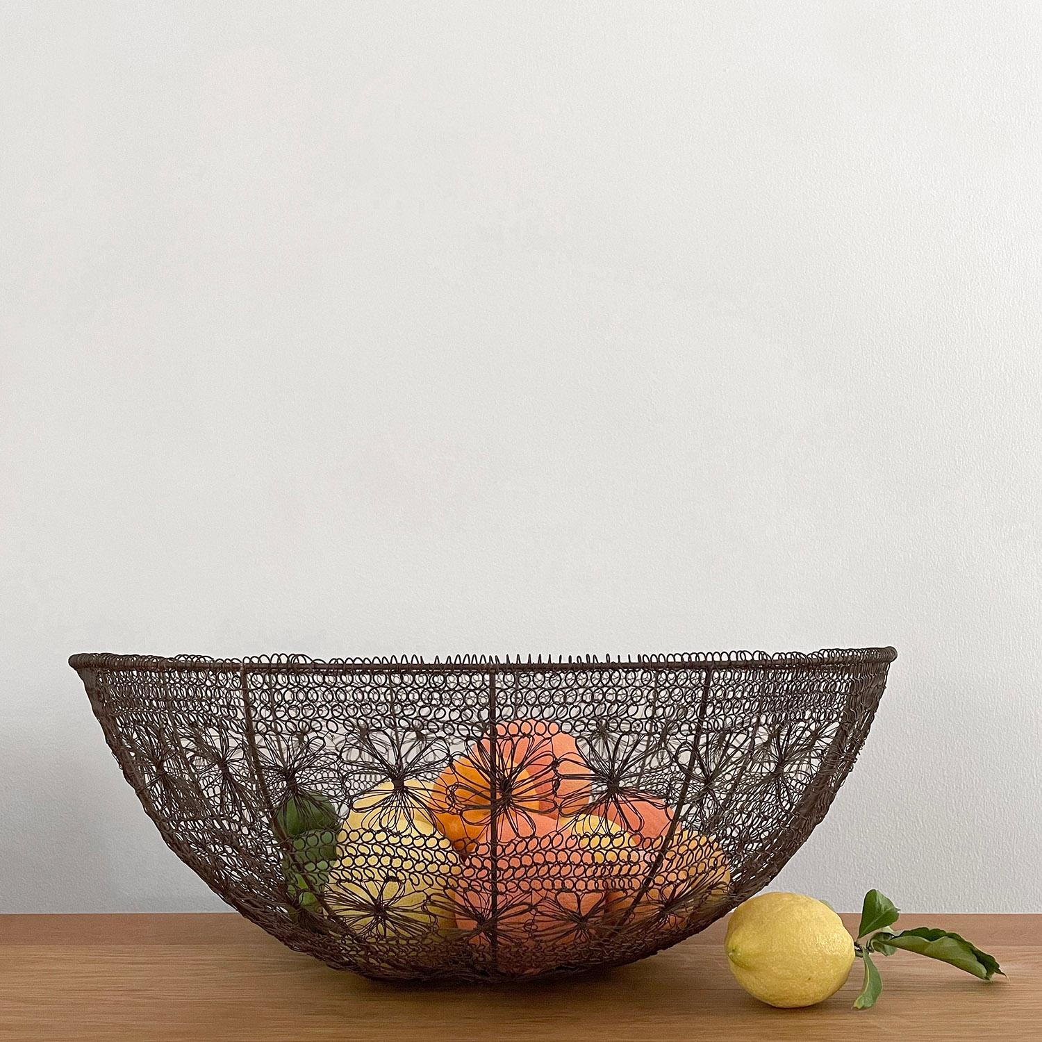 Rustic French metal floral mesh oversized basket 
Handcrafted artisanal piece 
Intricately woven wire mesh constructed in a series of rings
Each ring is made up of tiny interlocking loops or flowers 
Finished with a coiled banding detail
This large