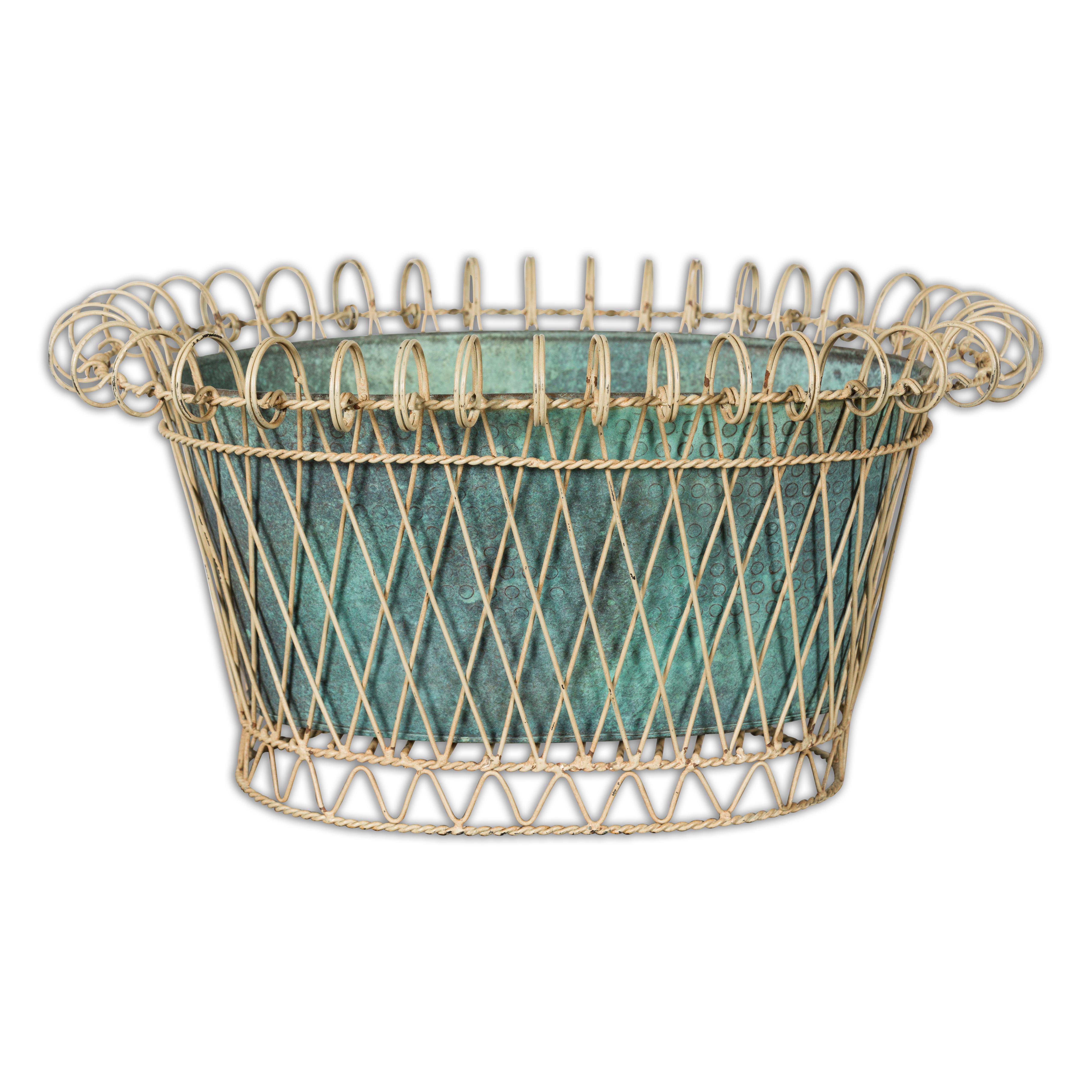 A rustic French oval shaped cachepot from the midcentury period with white painted metal frame surrounding a blue green liner adorned with hammered décor. Emanating rustic charm and midcentury elegance, this French oval-shaped cachepot is a timeless