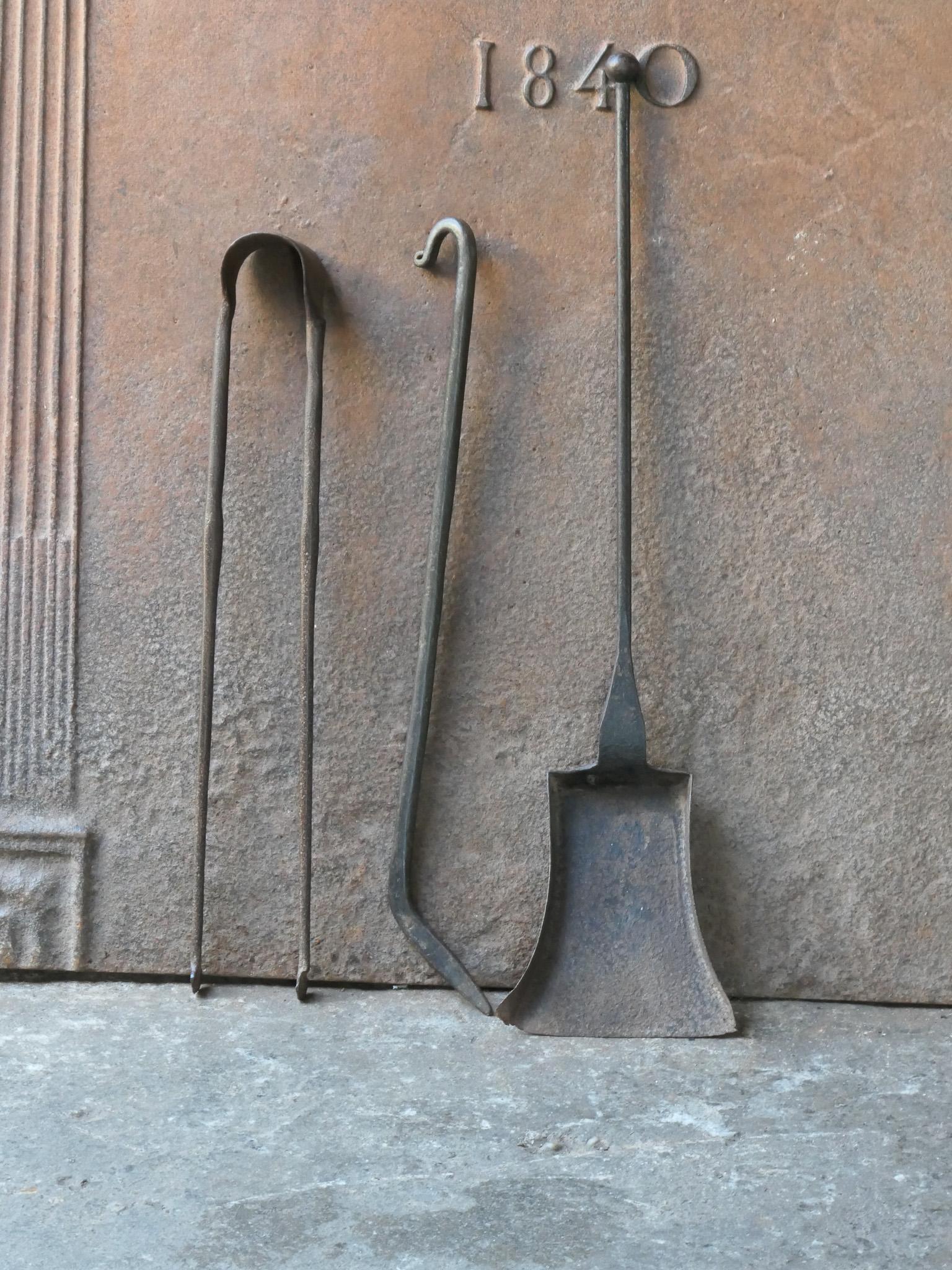 Ensemble d'outils de cheminée rustique français du 18e-19e siècle. L'ensemble d'outils comprend une pince à cheminée, une pelle et un tisonnier. Les outils sont en fer forgé. L'ensemble est en bon état et apte à être utilisé dans la cheminée.