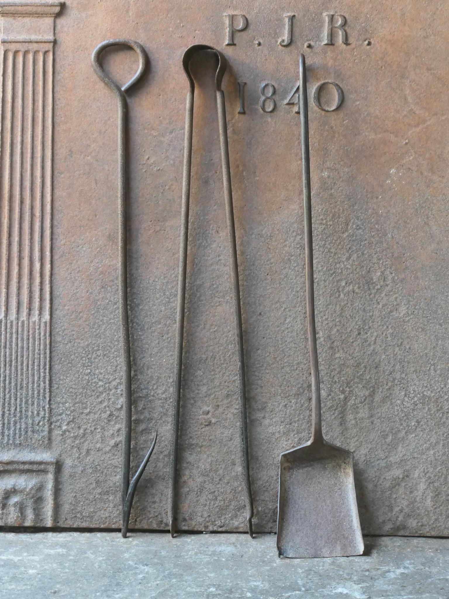 Ensemble d'outils de cheminée rustique français du 18e-19e siècle. L'ensemble d'outils comprend une pince à cheminée, une pelle et un tisonnier. Les outils sont en fer forgé. L'ensemble est en bon état et apte à être utilisé dans la cheminée.