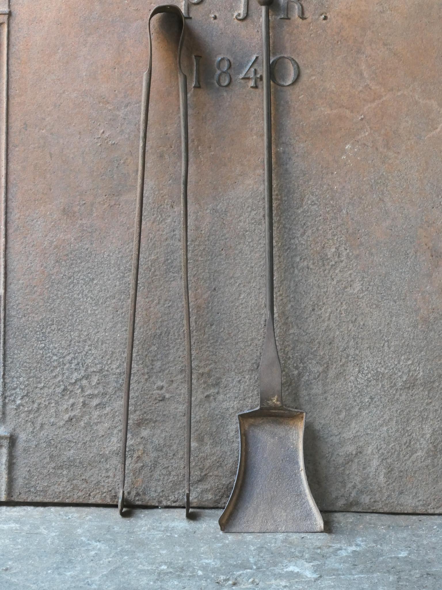 Rustic 18th-19th century French fireplace tool set. The tool set consists of fireplace tongs and a shovel. The tools are made of wrought iron. The set is in a good condition and fit for use in the fireplace.