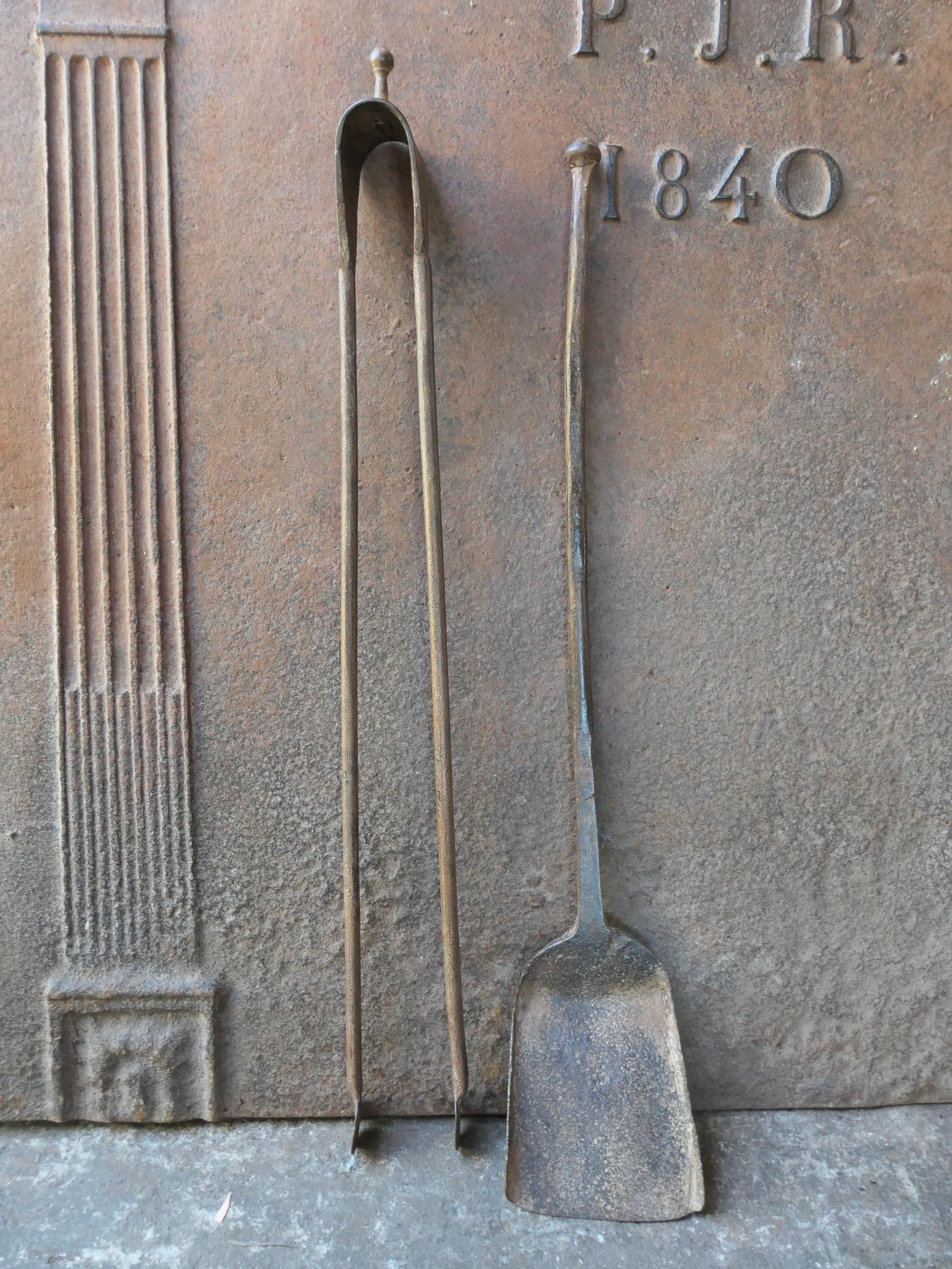 Rustic 18th-century French fireplace tool set. The tool set consists of fireplace tongs and a shovel. The tools are made of wrought iron. The set is in good condition and fit for use in the fireplace.
