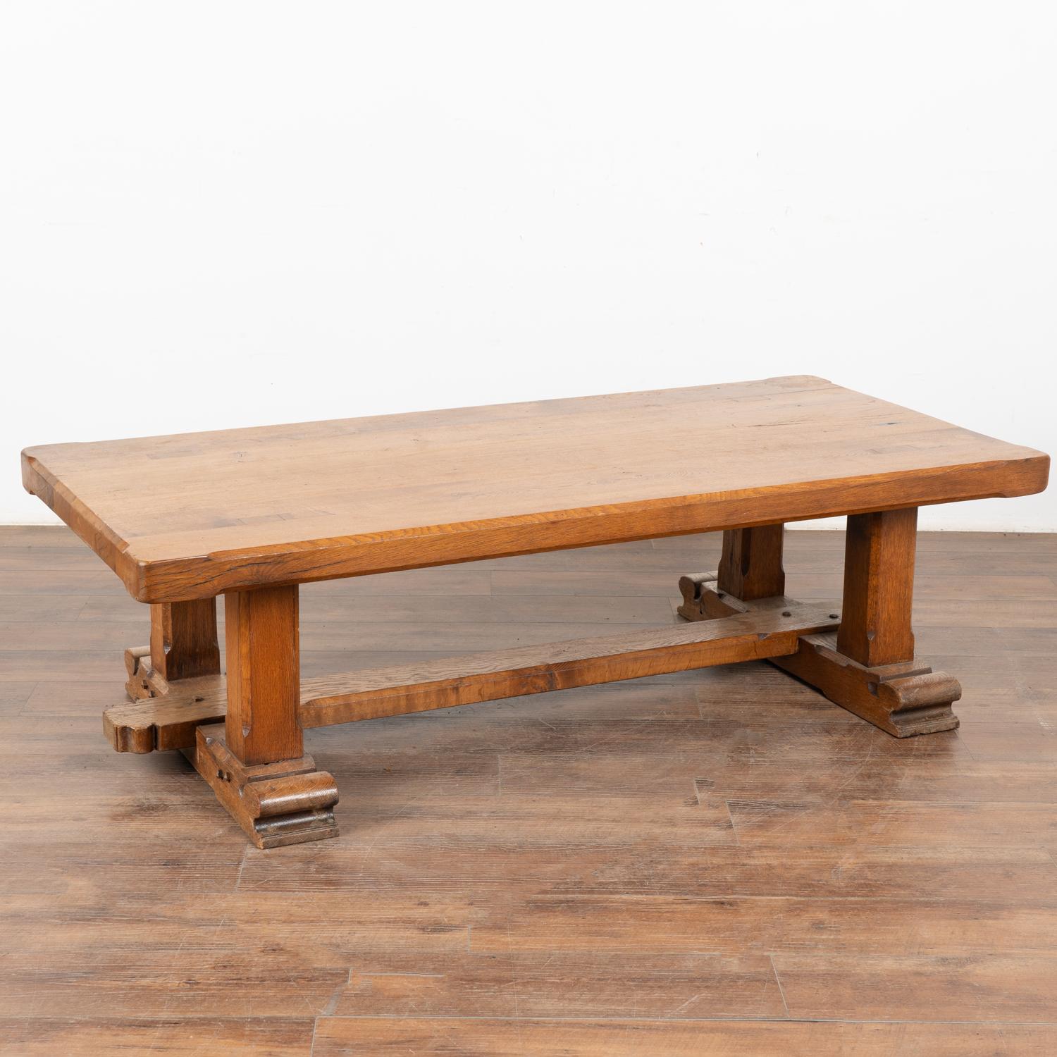The appeal of this heavy French oak coffee table comes from the rich patina of the wood. Every crack, ding, old knot and stain all add to the depth and richness found in the thick top. Note how the darker color of the legs inset into the top also