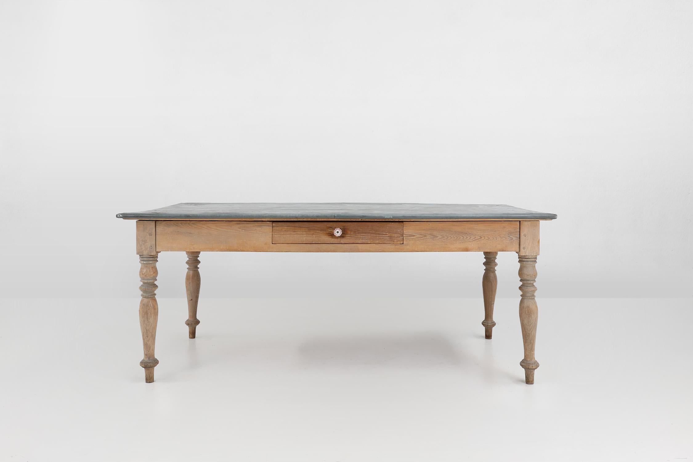 France / 1850 / dinner table / pine, zinc / Rustic / Mid-century

A rustic mid-century pine woode, table, made in France around 1850. This classic designed table has an overhanging robust zinc covered top and stands on 4 turned legs. This large,