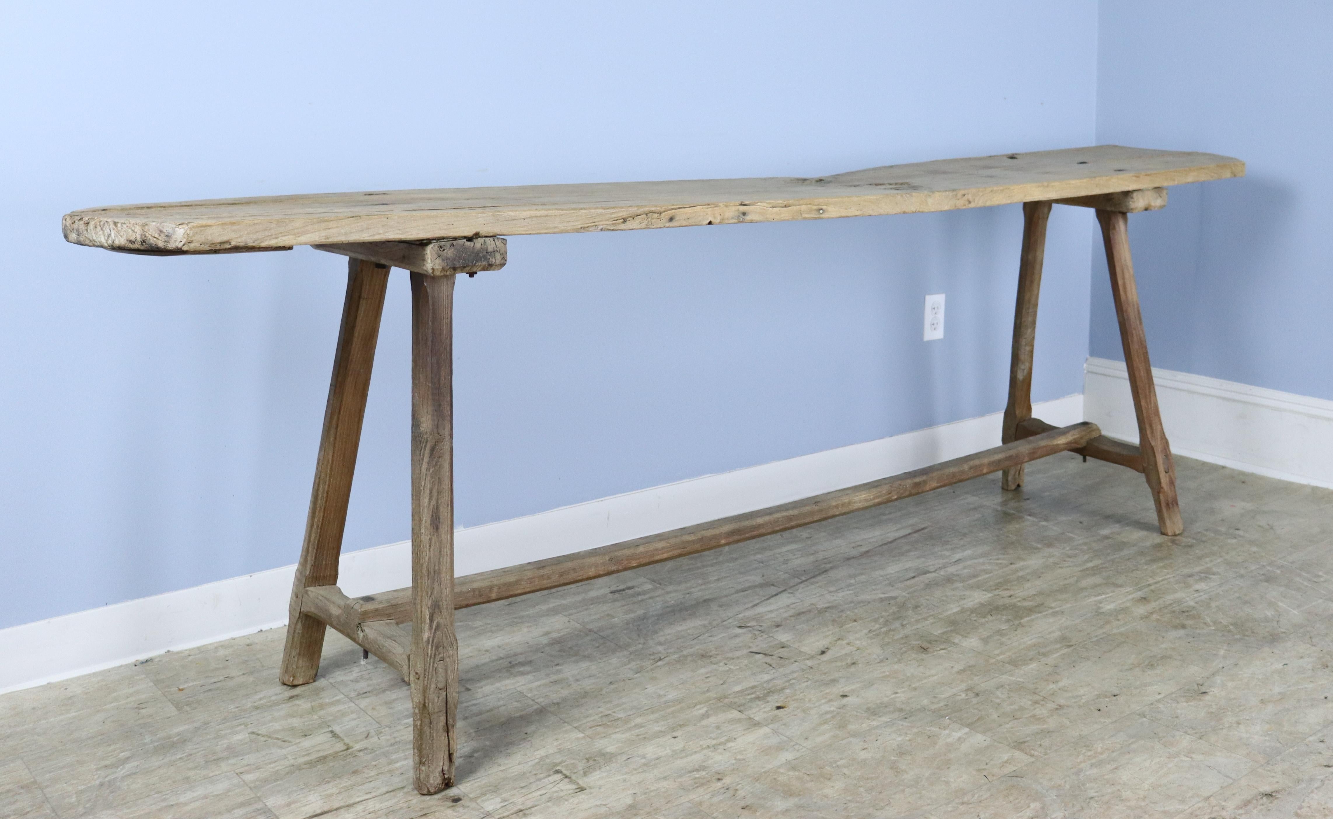 A well worn poplar serving or work table with lots of interesting wear and naturalistic grain and knotholes. The natural curves of the poplar planks give this piece a truly organic country look. We believe the piece has been bleached naturally over