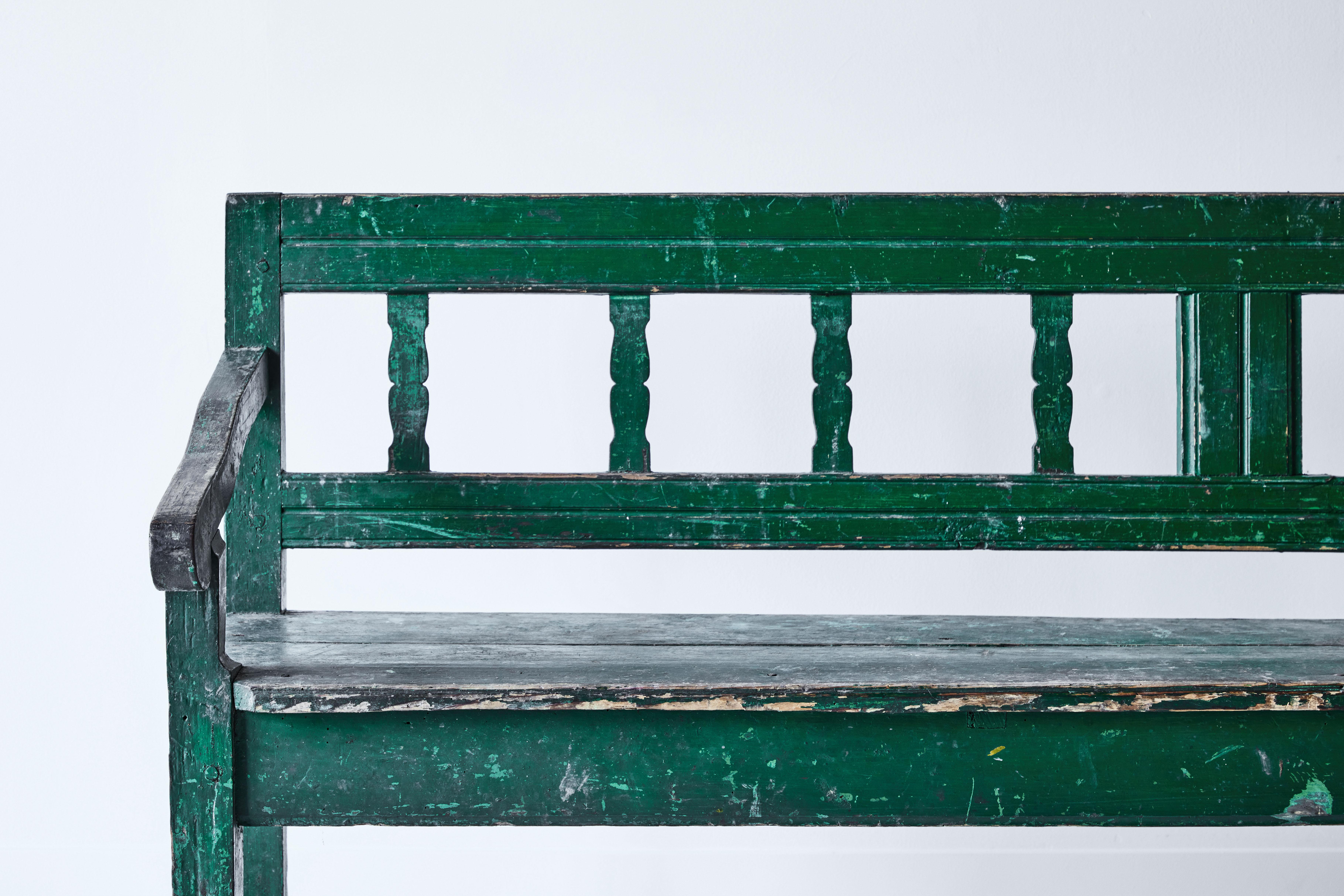 This beautifully rustic French painted bench features original green paint and a lovely patina. The paint has been distressed throughout the years revealing the natural wood below. It is the perfect piece for an entryway or porch. This bench has
