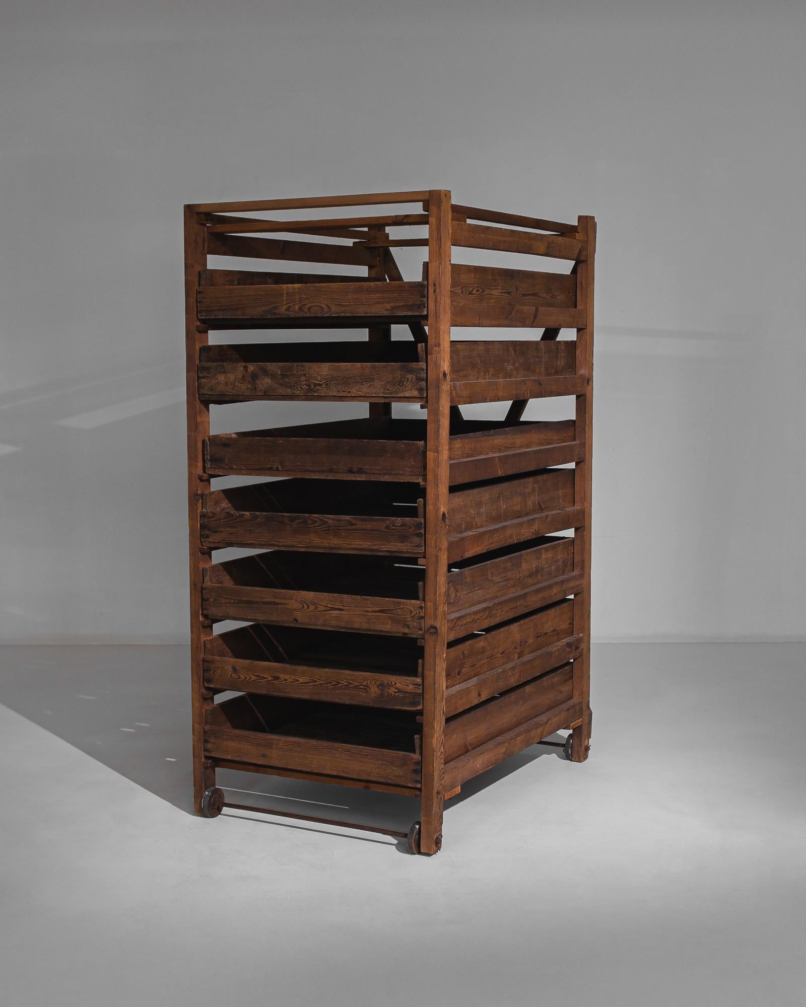 This antique rack of wooden shelves with cast iron wheels was made in France. The pull-out box shelves feature slatted bases and recall the racks used in large kitchens to store vegetables and to dry fruit. It is sturdily constructed with rustic