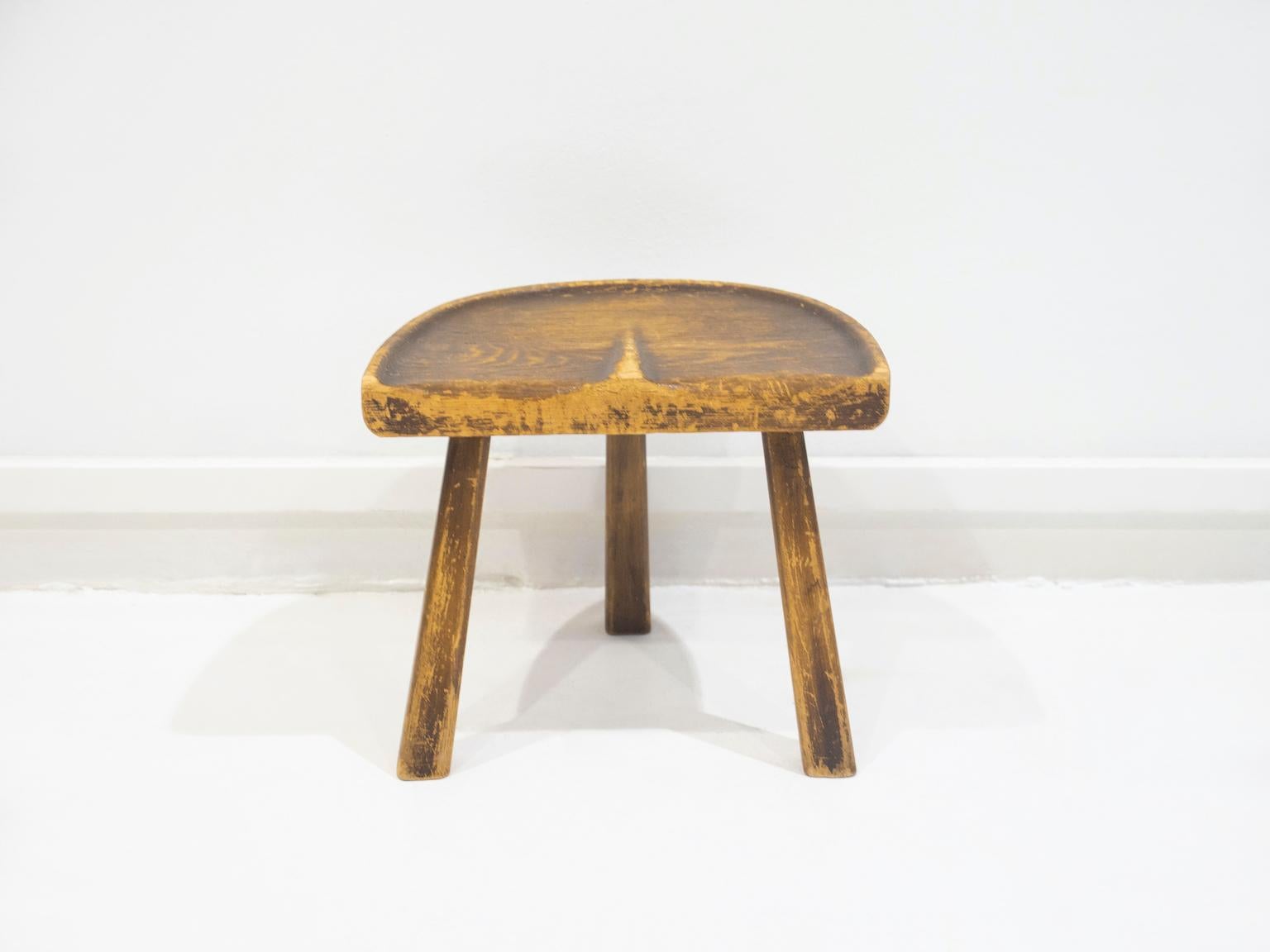 Vintage wooden stool made in France in the 1950's. The stool has an ergonomic seat and three legs, resembling a simple milk stool. Ideal to decorate rustic areas.