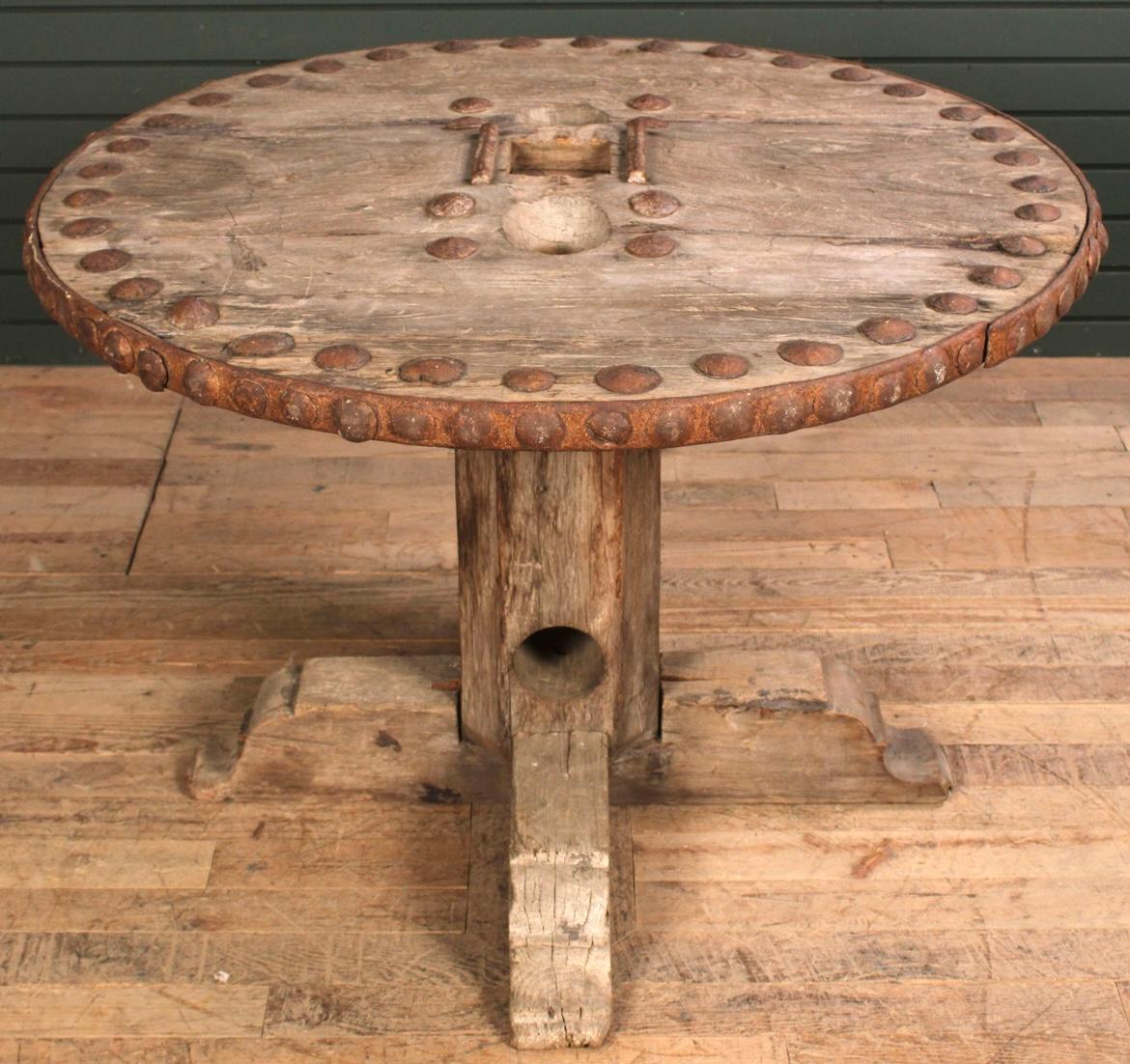 Una mesa de jardín rústica compuesta por elementos recuperados, el gran tablero circular con clavos de hierro incrustados y otros herrajes de hierro. Se desmonta en 4 secciones para facilitar su traslado y almacenamiento. 