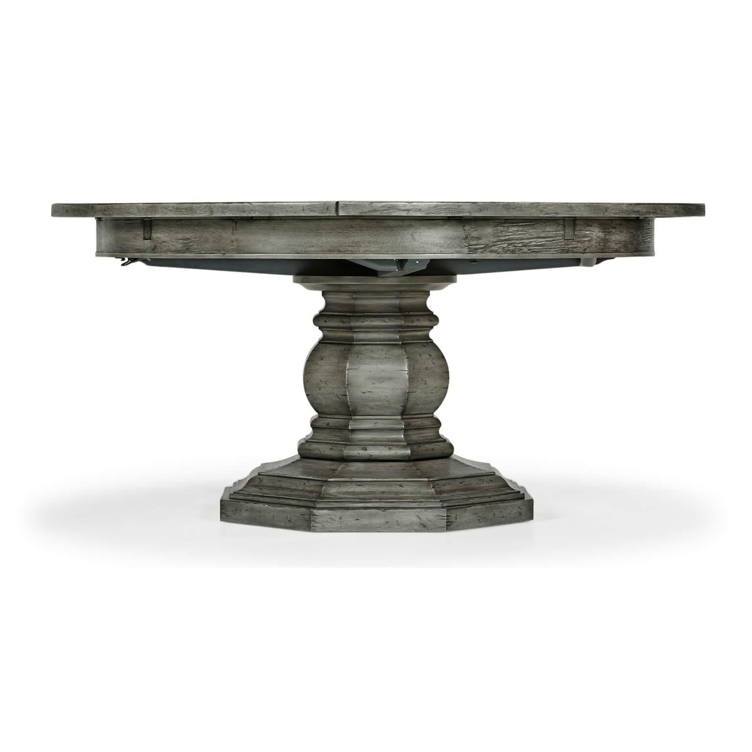 Antique dark grey topped circular dining table with a rustic finish showing exposed saw marks set on a substantial baluster stem base, the table extending via an ingenious mechanism of self-storing hinged fold-out leaves within. 

Open dimensions: