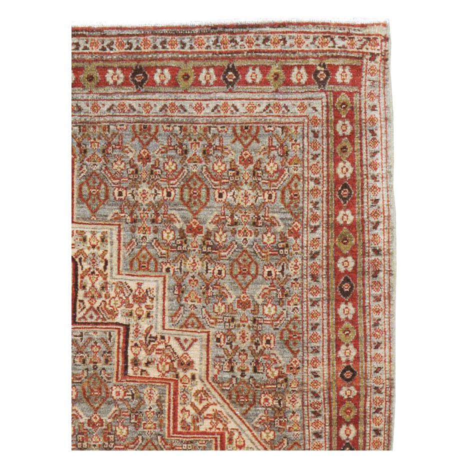 An antique Persian Senneh throw rug handmade during the early 20th century with an overall rustic appeal in shades of grey, red, and cream.

Measures: 3' 8