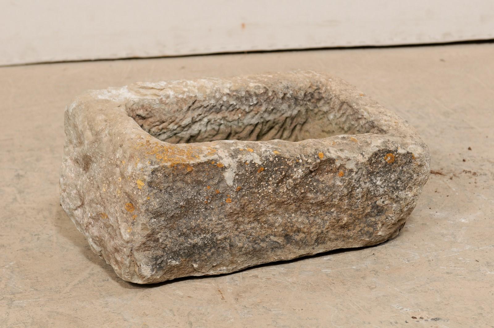 A Spanish carved stone trough from the 19th century. This antique trough from Spain, with it's overall rectangular shape, has been hand carved out of a single piece of stone, having a nicely textured surface. In addition to standing alone as a