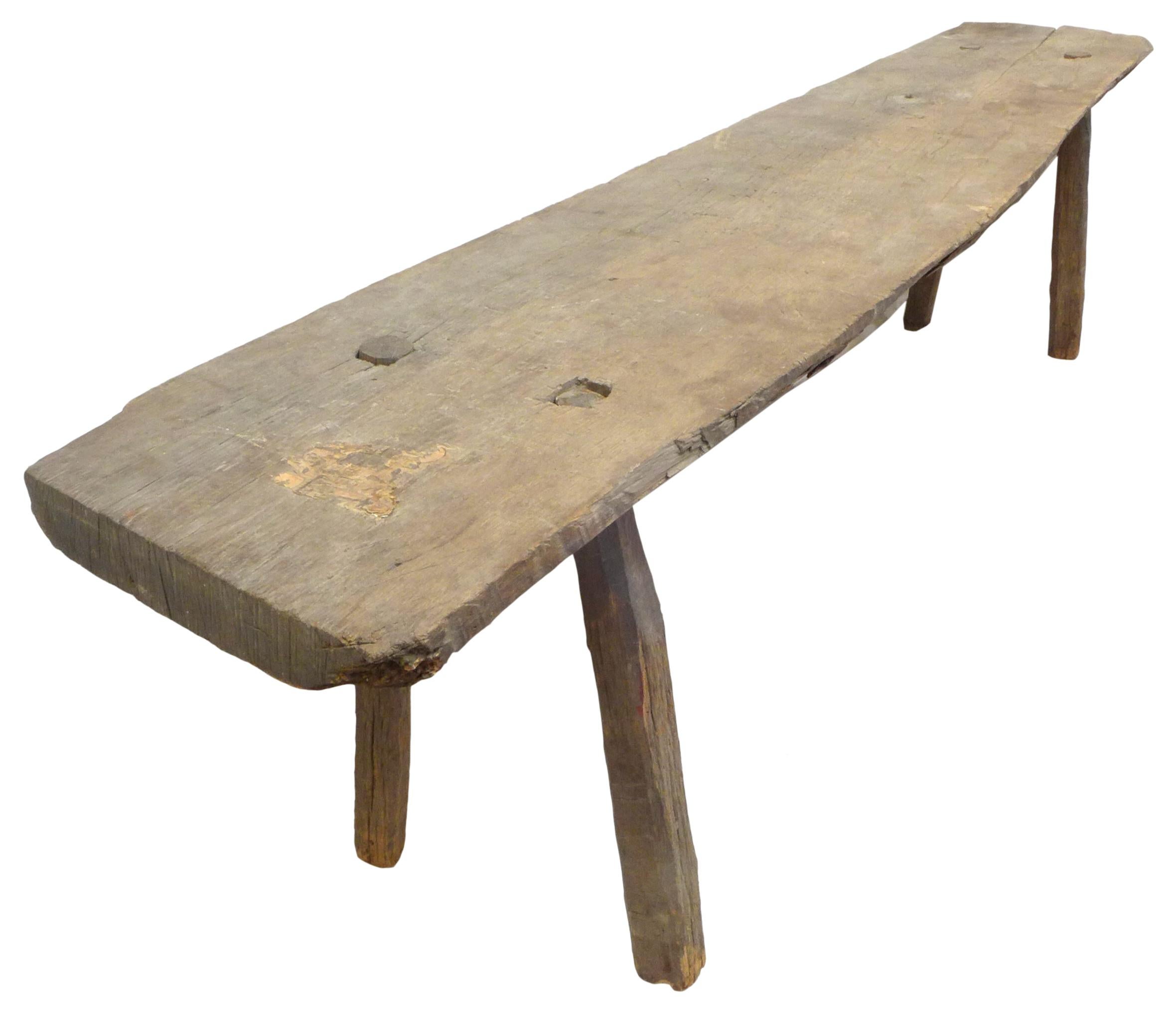 A fantastic rustic, hand-hewn wood low console table or bench. An austere, reduced form; a raw-edge wood plank with four cylindrical mortise and tenon legs. Wonderful surface and patina from age. Great, unusual scale. A powerful and evocative