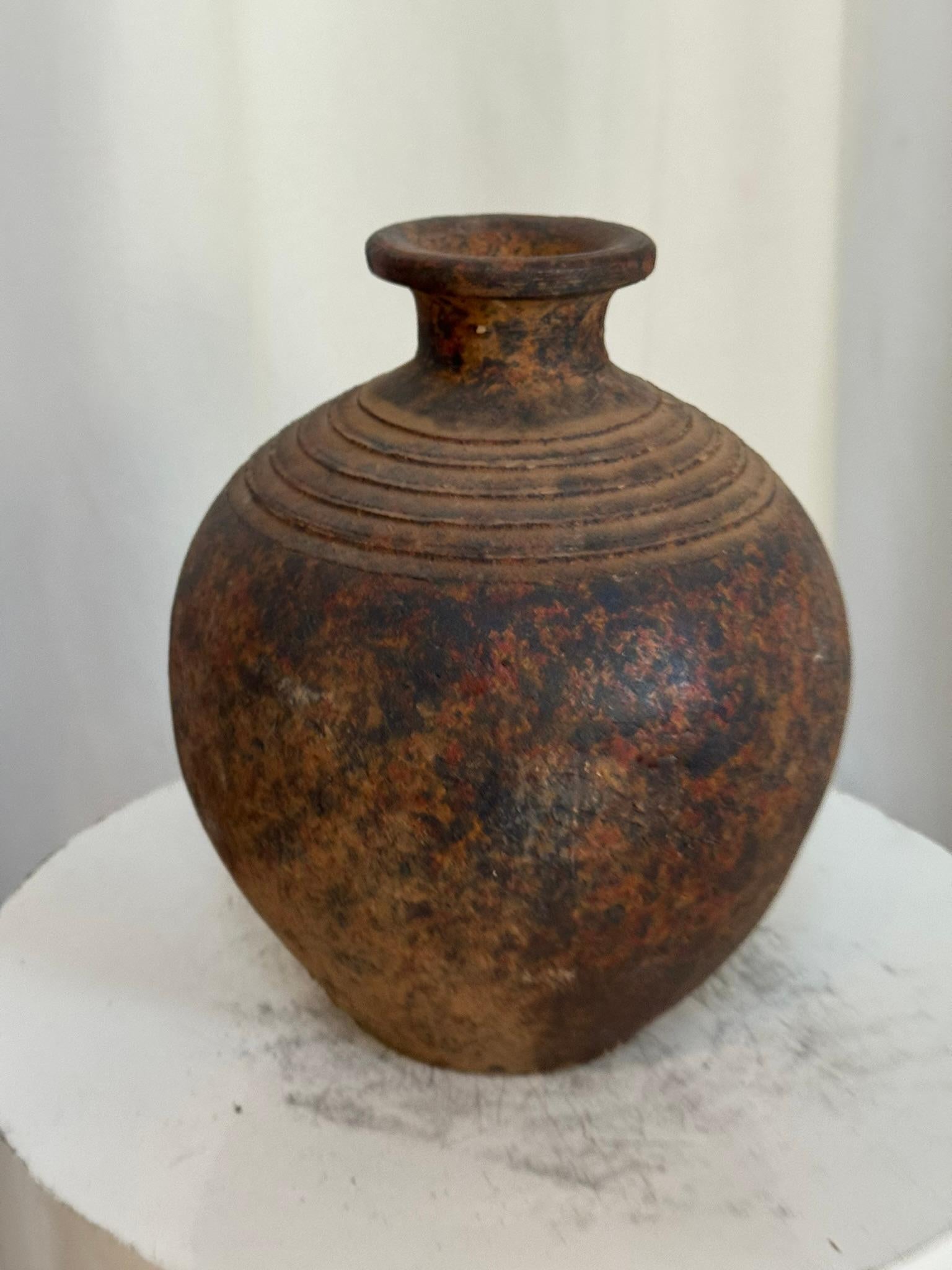 Diese exquisite, handgefertigte Vase aus Studio-Töpferware strahlt einen rustikalen Charme aus, der sowohl durch handwerkliches Können als auch durch den sanften Lauf der Zeit entsteht. Seine natürlich gealterte Patina mit weichen, matten Tönen und