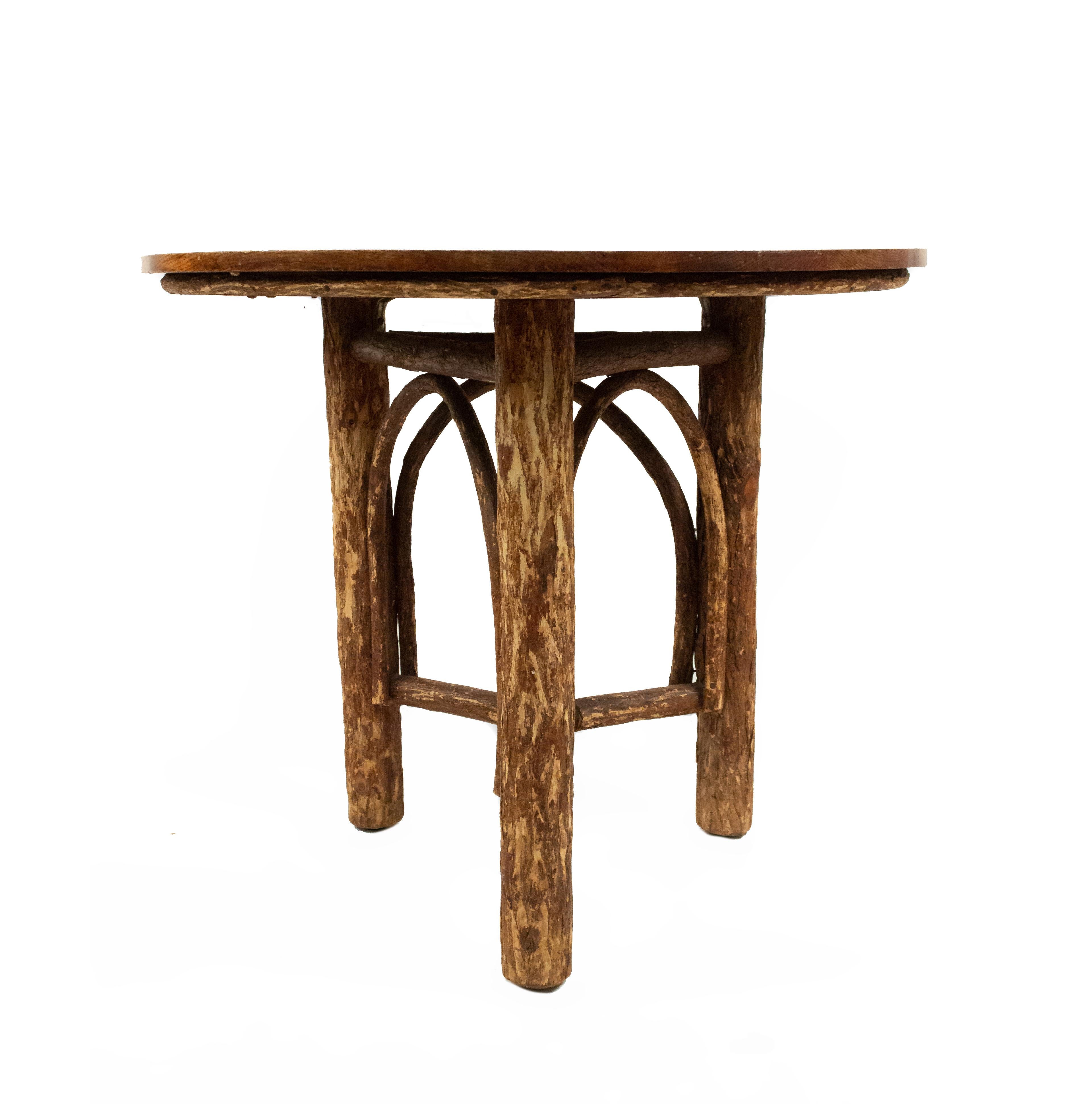 Rustic Old Hickory-style (late 20th century) round end table with exposed bark legs and bentwood details along sides with a pine top.
         