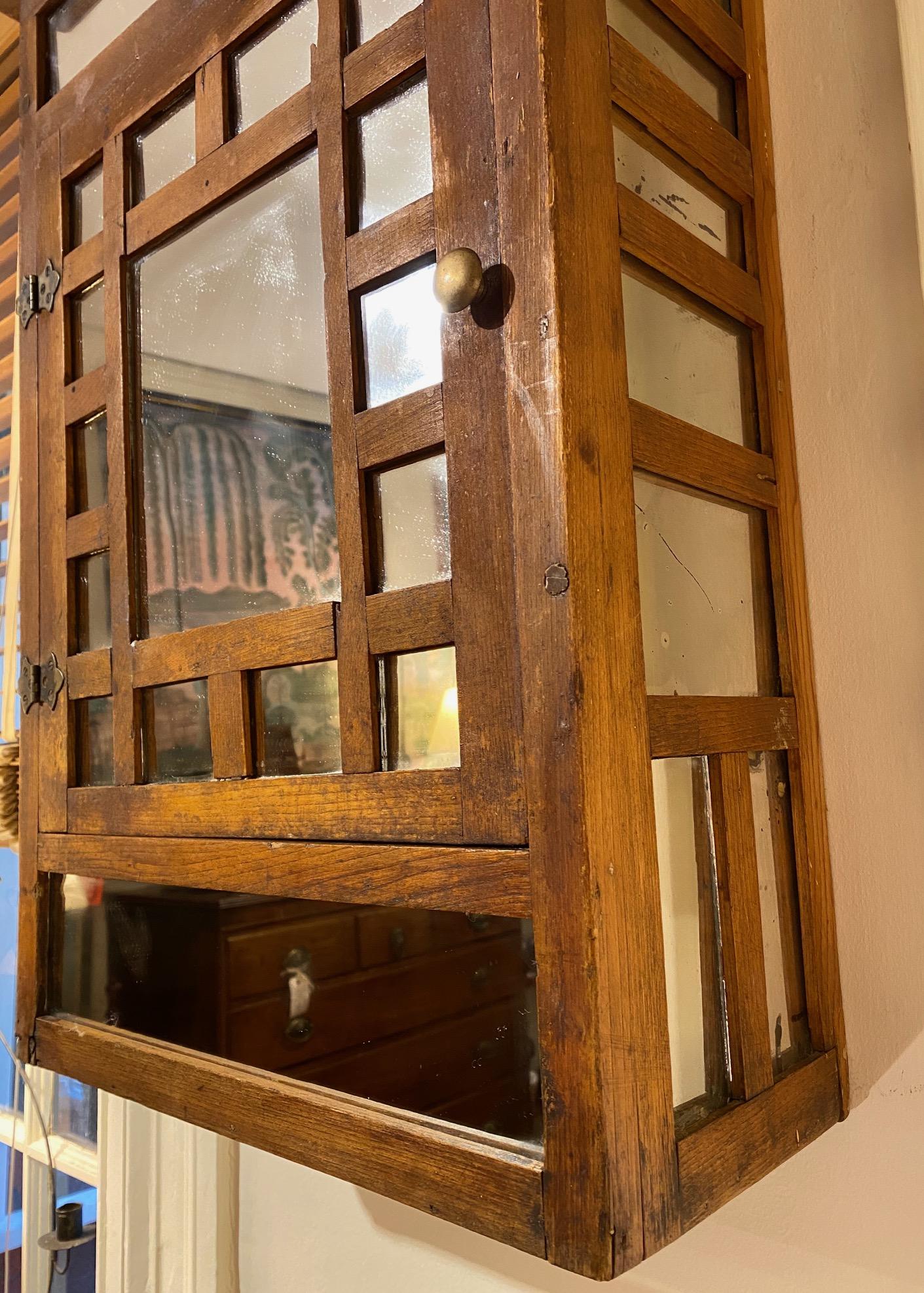 Antique Rustic Home Made Oak Mirrored Hanging Cupboard, circa 1890, from Quebec or northern Vermont, a lovely  cabinet with a number of mirror panels set on the door and sides. A home-built farmhouse piece, crude and charming, and very unusual.

The