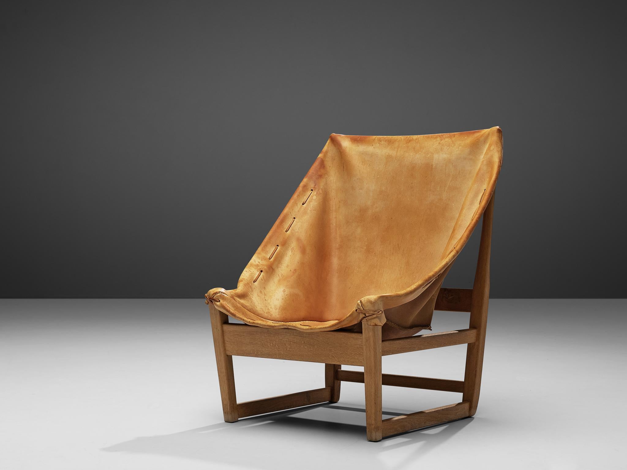 Hunting chair, leather, oak, France, 1960s

This hunting chair stands out with its beautiful patinated cognac leather seating.
The leather is wrapped around the edges of the frame and hangs freely in the middle. The edges of the leather are