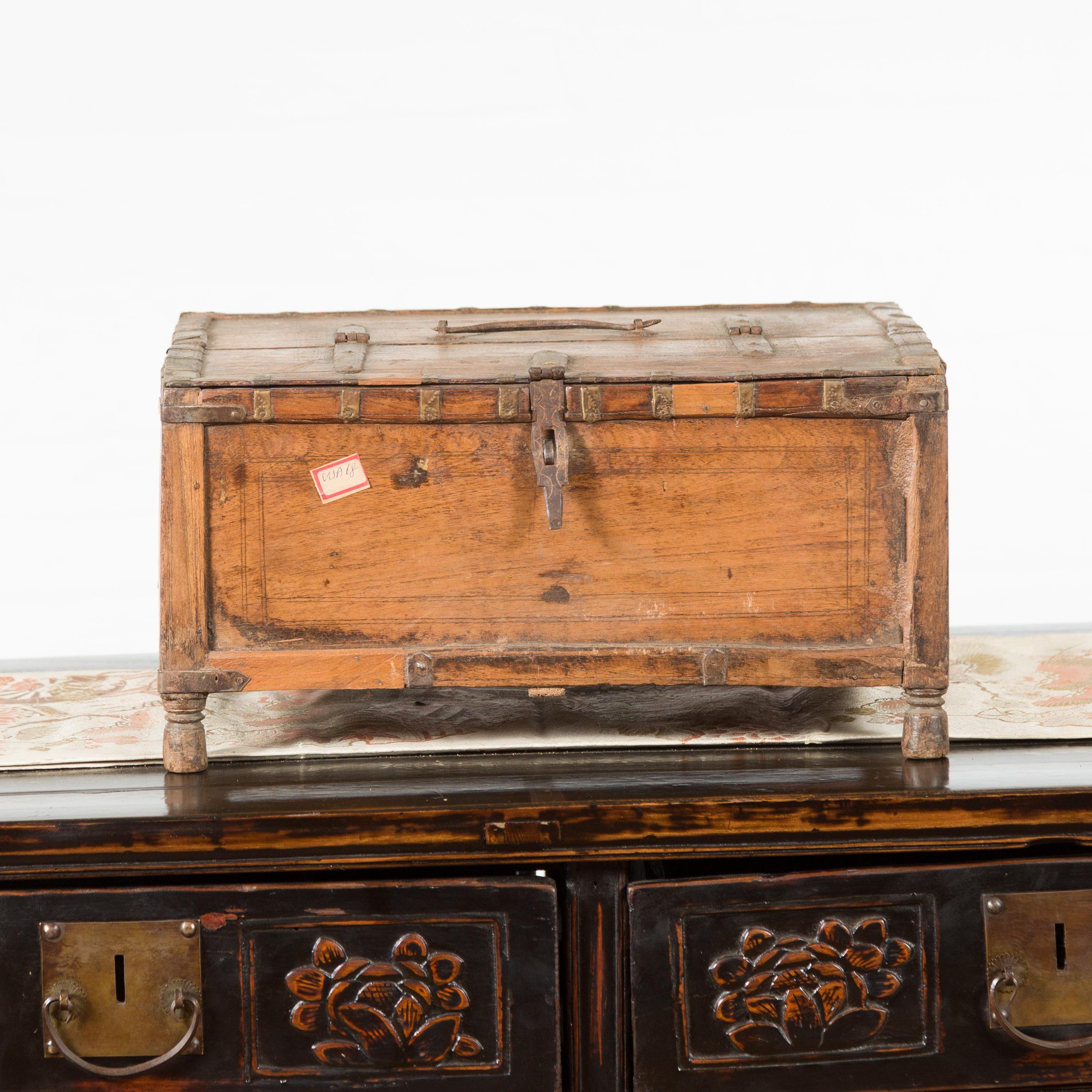 An Indian rustic wooden box from the 19th century, with nicely weathered appearance, iron details and incised motifs. Created in India during the 19th century, this wooden box features a rectangular lid adorned with concentric circles, half opening