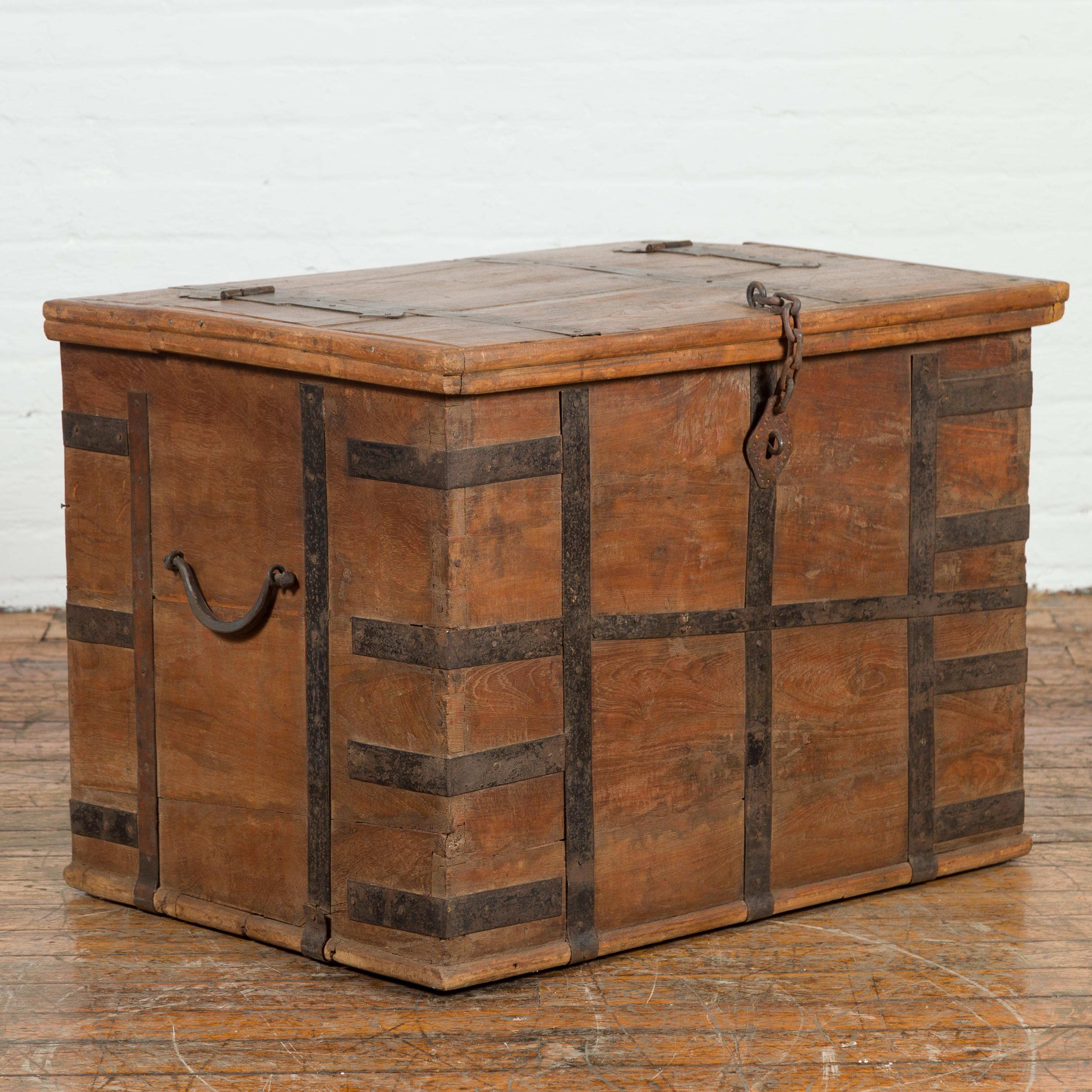 An Indian rustic wooden trunk from the 19th century with iron hardware and nicely weathered patina. Created in India during the 19th century, this wooden trunk features a rectangular top partially opening to reveal an interior offering convenient