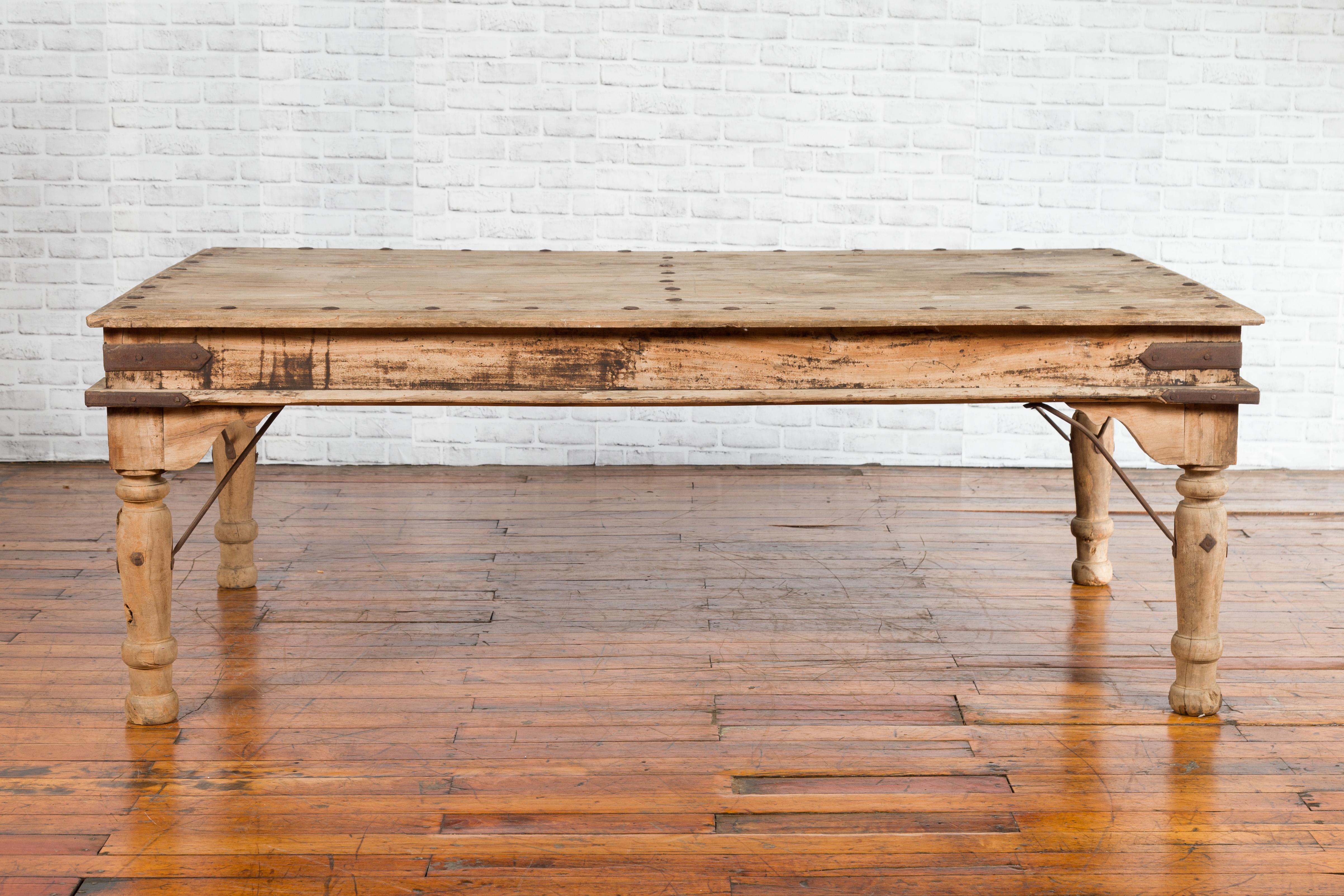 An antique rustic Indian low table from the early 20th century, with iron details. Created in India during the early years of the 20th century, this low table features a rectangular planked top with iron studs, sitting above a simple apron accented