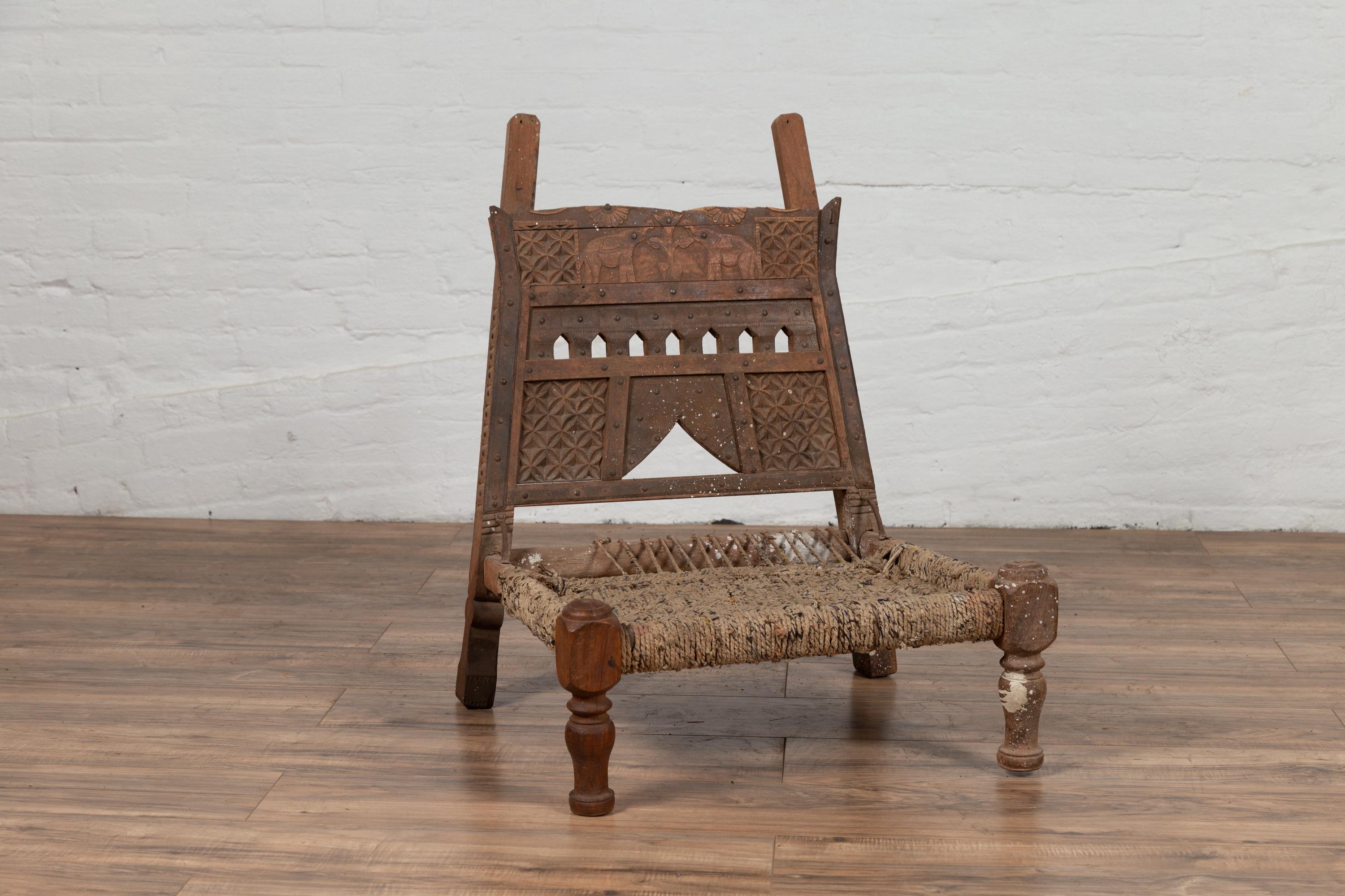 Carved Rustic Indian Low Wooden Chair with Rope Seat and Weathered Appearance For Sale