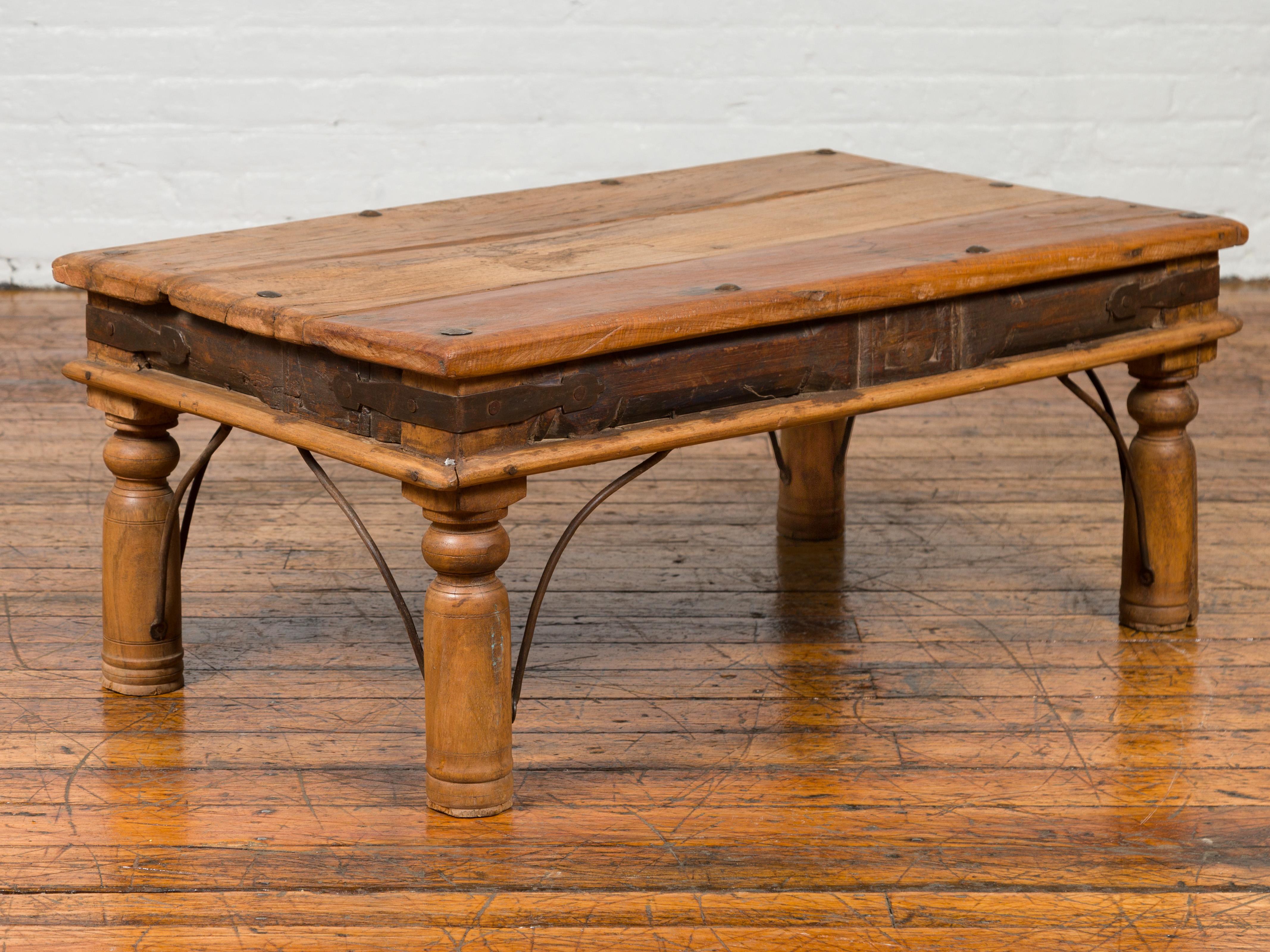 An antique rustic Indian sheesham wood low coffee table from the 19th century with iron nailheads and baluster legs. Crafted in India during the 19th century, this coffee table features a rectangular planked top with iron nailheads, sitting above an
