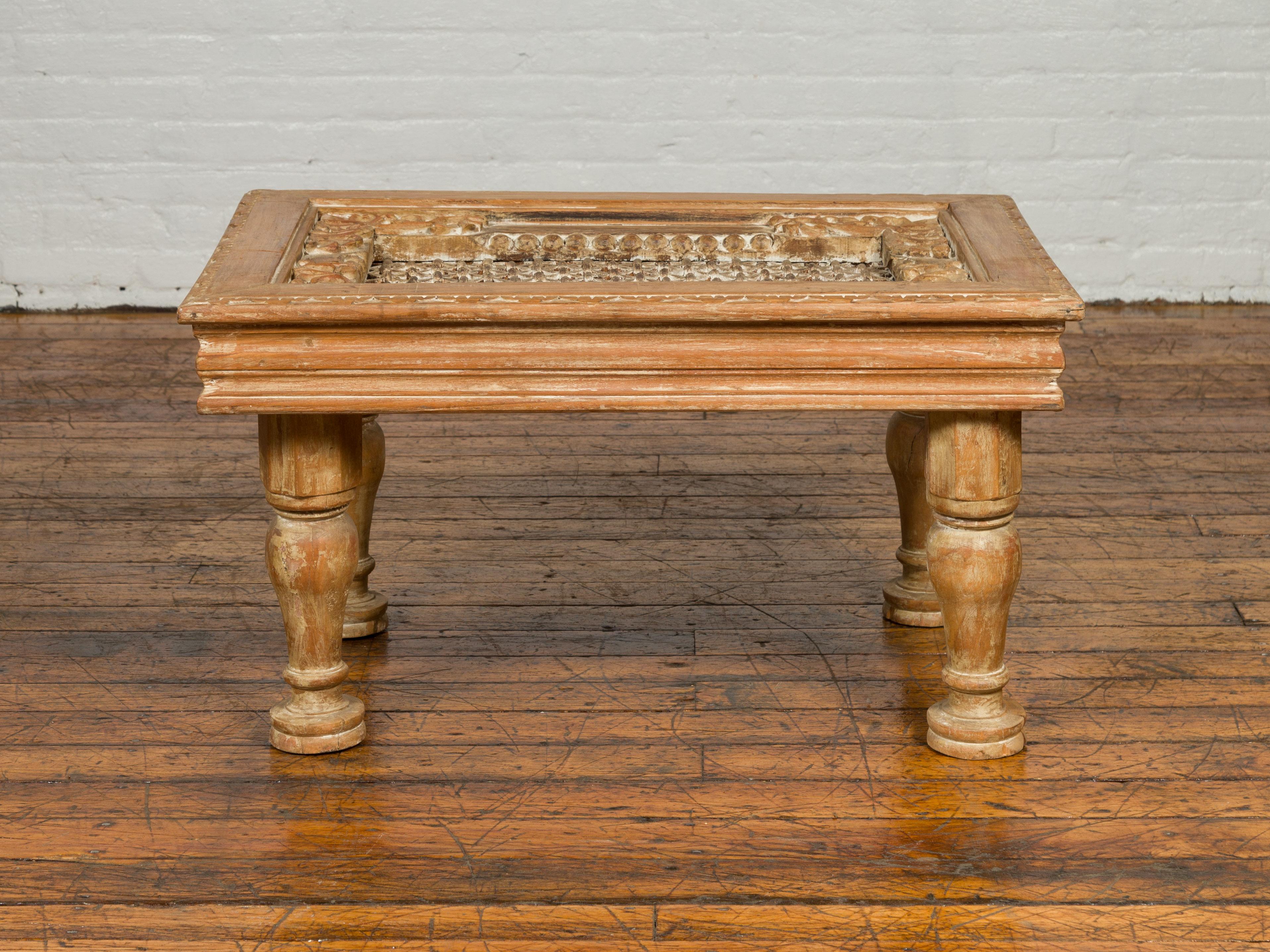 An Indian sheesham wood cocktail table from the early 20th century, with window grate top and turned legs. Born in India during the early years of the 20th century, this cocktail table features a rectangular iron top surrounded by carved foliage.
