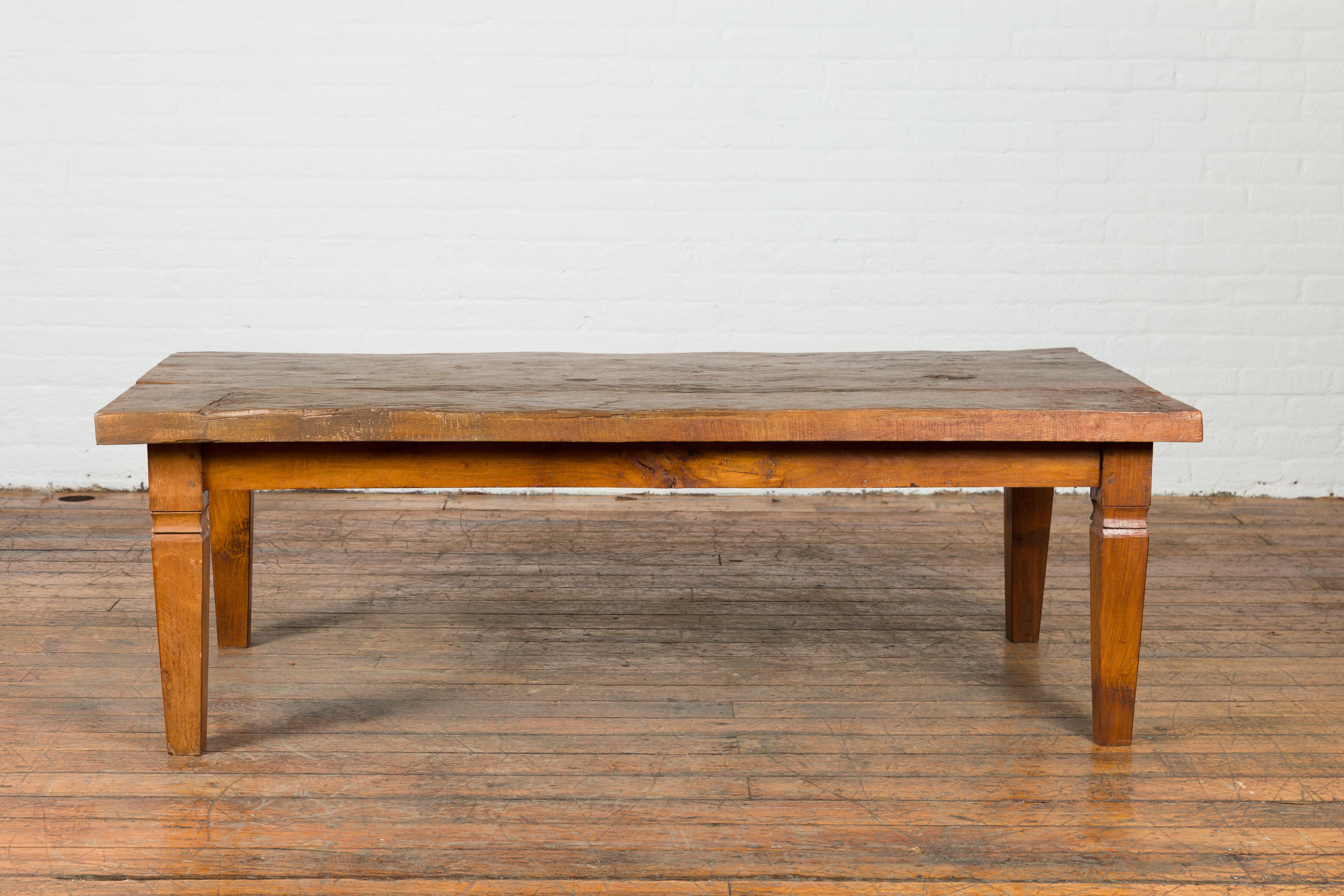 A rustic Indonesian antique wooden coffee table from the 19th century, made from a slab of wood. Created in Indonesia during the 19th century, this coffee table draws our attention with its rustic planked top with nicely weathered appearance,