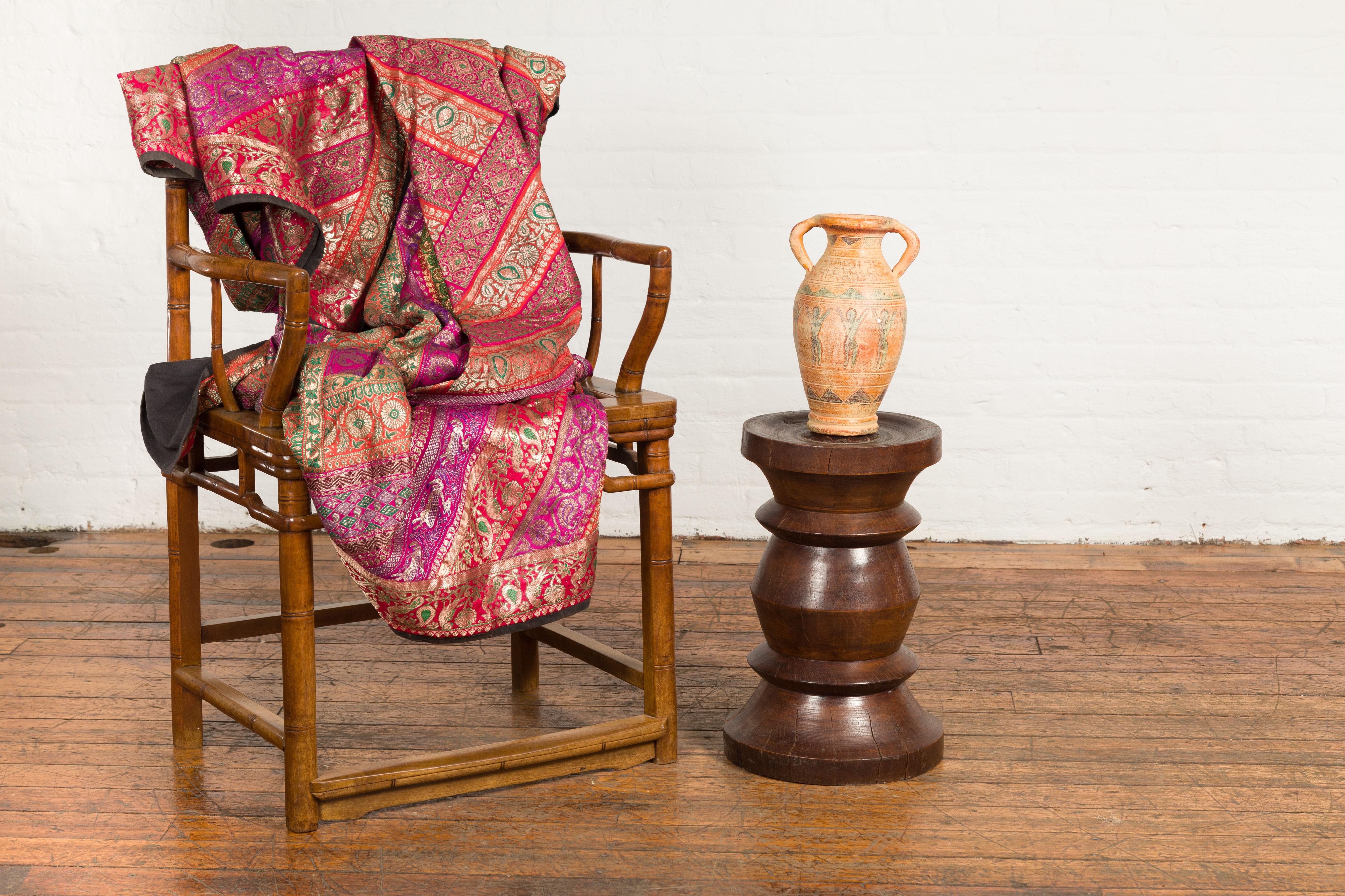 An Indonesian turned wooden stool from the 19th century with brown patina. Crafted in Indonesia during the 19th century, this stool is made of solid turned wood. Showcasing an hourglass reminiscent shape, the stool is topped with a circular seat