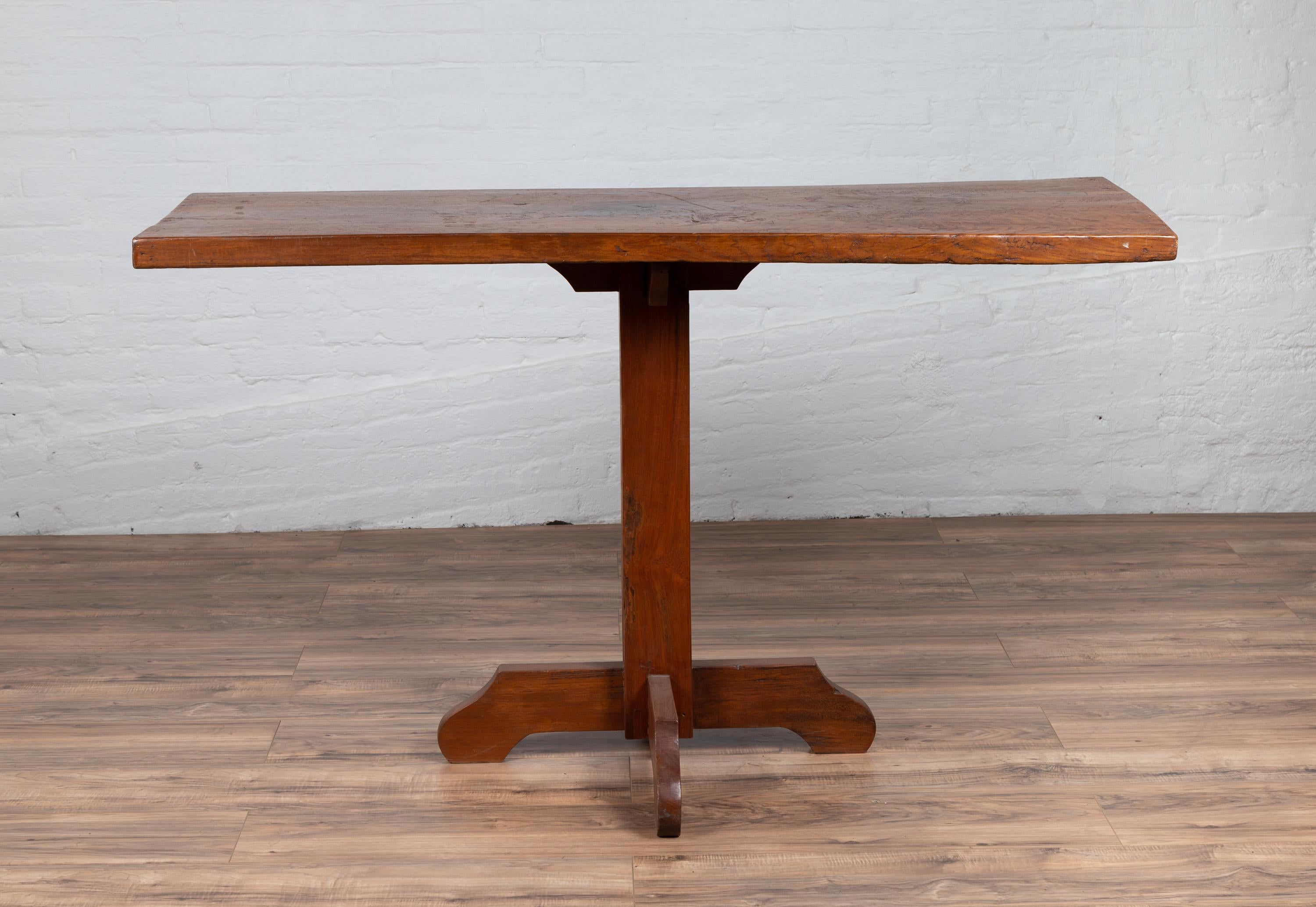 An antique Indonesian rustic console table from the early 20th century, with single plank top and quadripod base. Born in Indonesia during the early years of the 20th century, this console table charms us with its unpretentious look and rustic